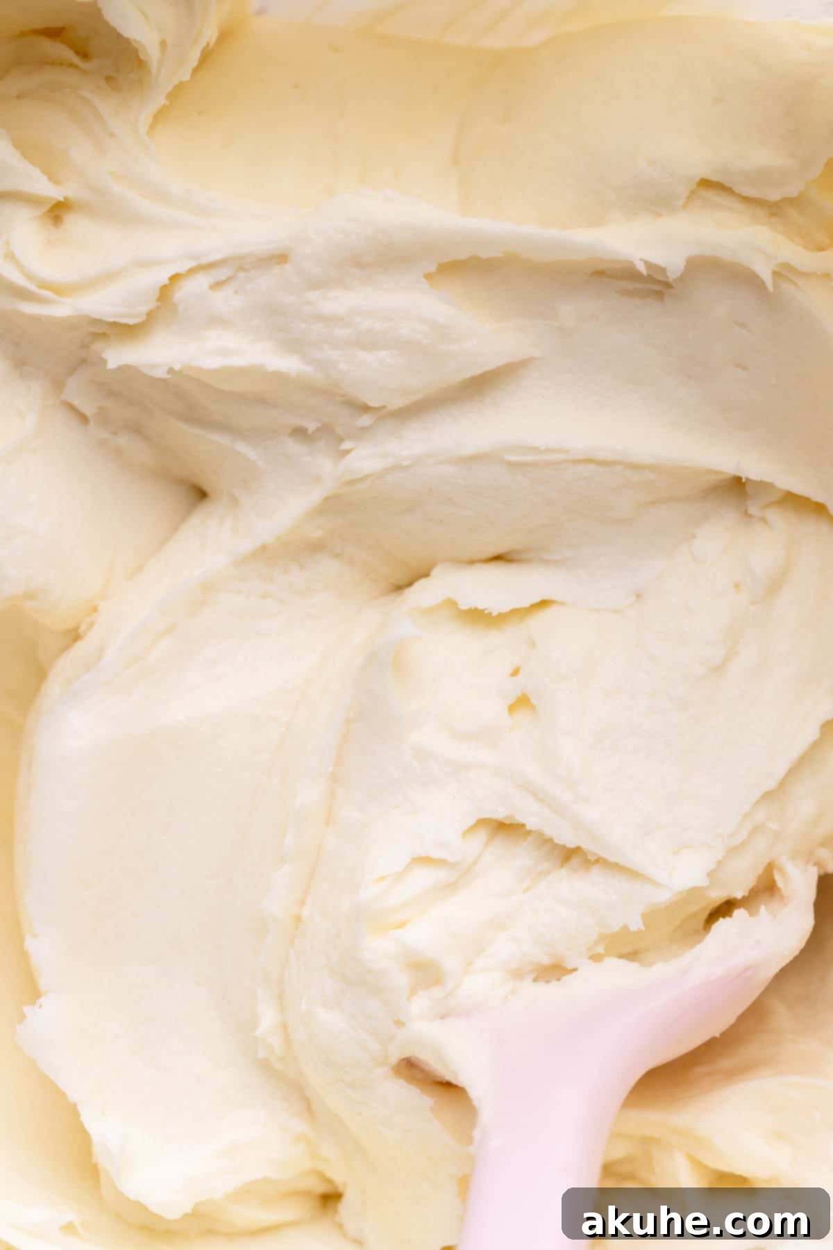 Festive Sprinkled Cake 7 Close-up of creamy white cream cheese frosting in a glass mixing bowl, ready to be used.