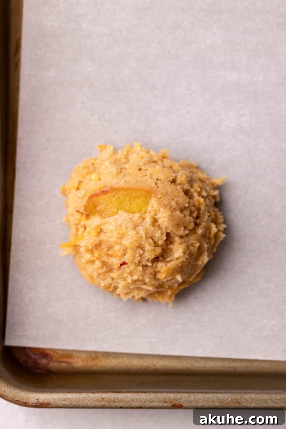 Sun-Kissed Peach Treats 8 A perfectly portioned cookie dough ball placed on a parchment-lined cookie sheet, ready for the oven.
