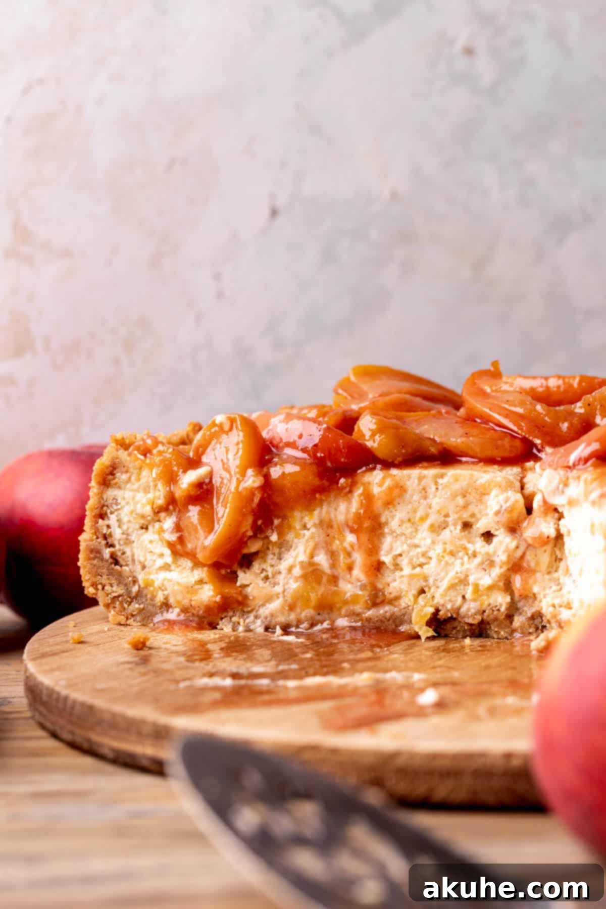 Luscious Peach Cheesecake 11 A beautiful side view of a tall, perfectly layered peach cheesecake, showcasing its height and creamy texture.