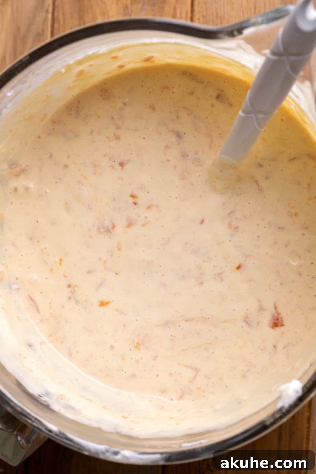 Luscious Peach Cheesecake 7 Rich, creamy peach cheesecake batter in a clear glass mixing bowl, ready for baking.