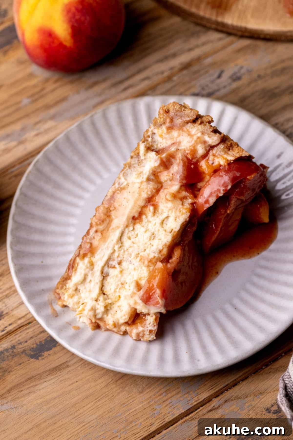 Luscious Peach Cheesecake 10 A perfectly sliced piece of peach cheesecake, showing the distinct layers and creamy texture on a white plate.