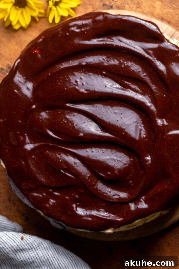 Smooth, glossy chocolate ganache spread across the top of a chilled cheesecake.