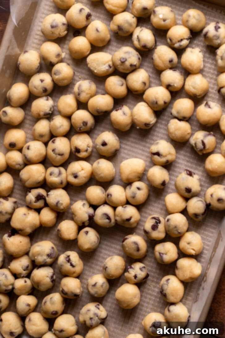 Small, rolled edible cookie dough balls arranged on a baking sheet.