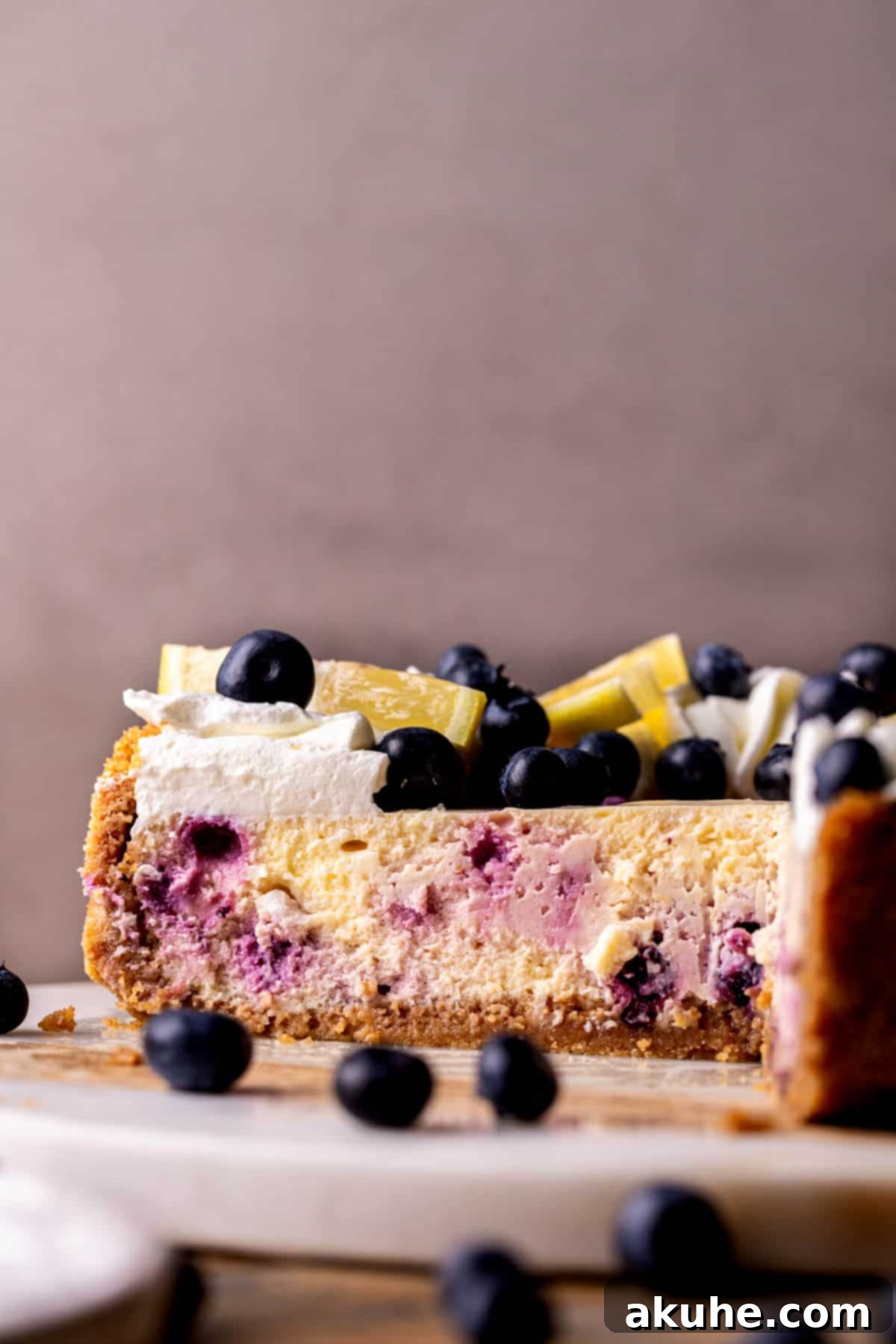 Zesty Lemon Blueberry Cheesecake 3 Side view of a perfectly baked lemon blueberry cheesecake, showing its distinct layers.