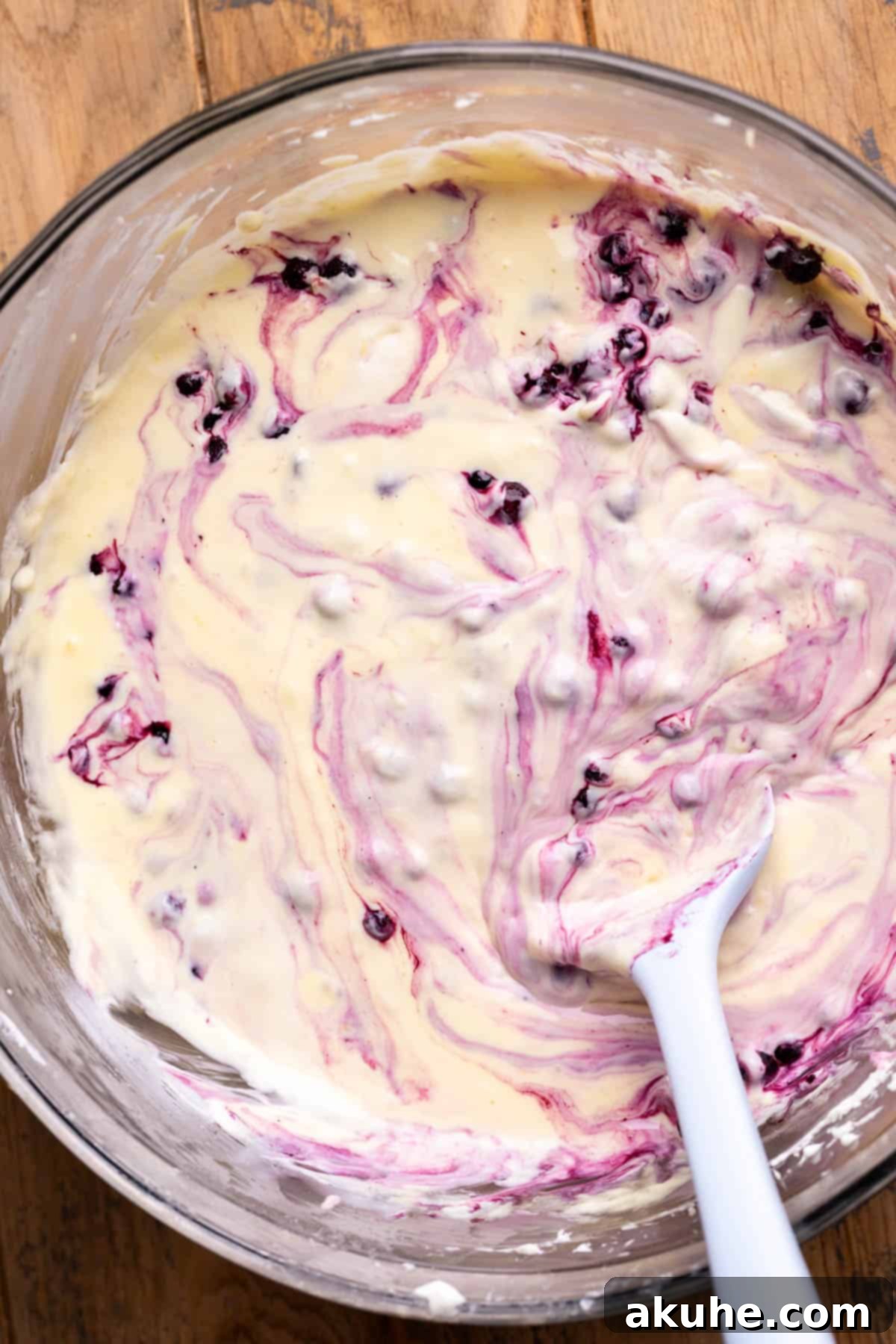 Zesty Lemon Blueberry Cheesecake 6 Wild blueberries being gently folded into the creamy lemon cheesecake batter, creating beautiful swirls.