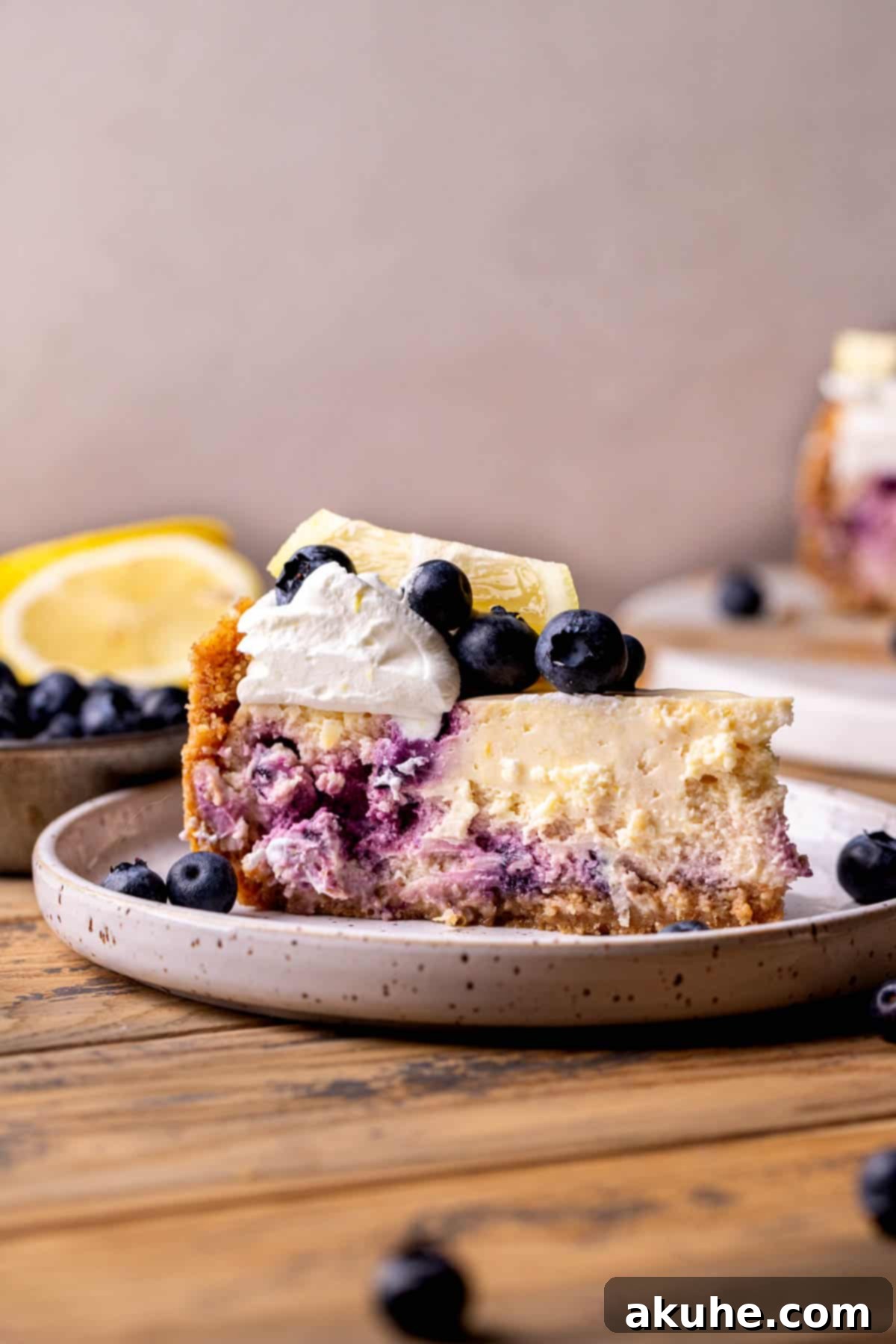Zesty Lemon Blueberry Cheesecake 9 A perfectly cut slice of lemon blueberry cheesecake on a white plate, showcasing its creamy texture.