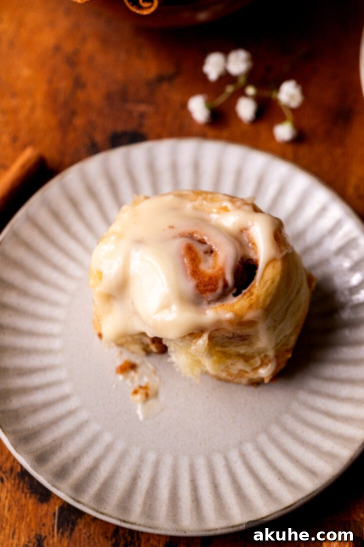 A single mini cinnamon roll on a small plate, ready to be eaten.