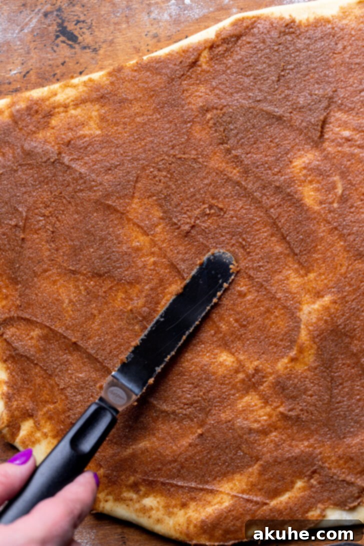 Spreading cinnamon sugar filling evenly across the dough.