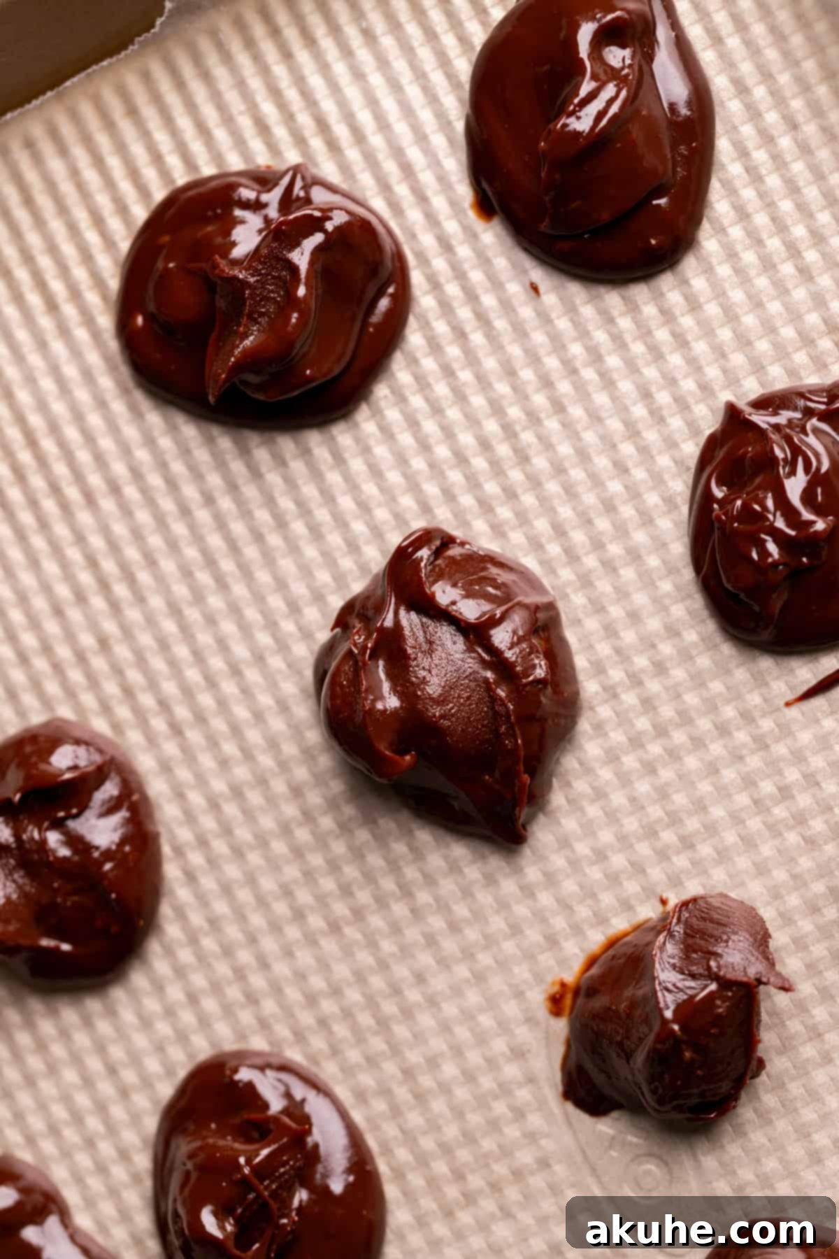 Fudgy Chocolate Delights 4 Individual chocolate ganache dollops neatly arranged on a wax paper-lined baking pan, frozen and ready for stuffing into cookies.