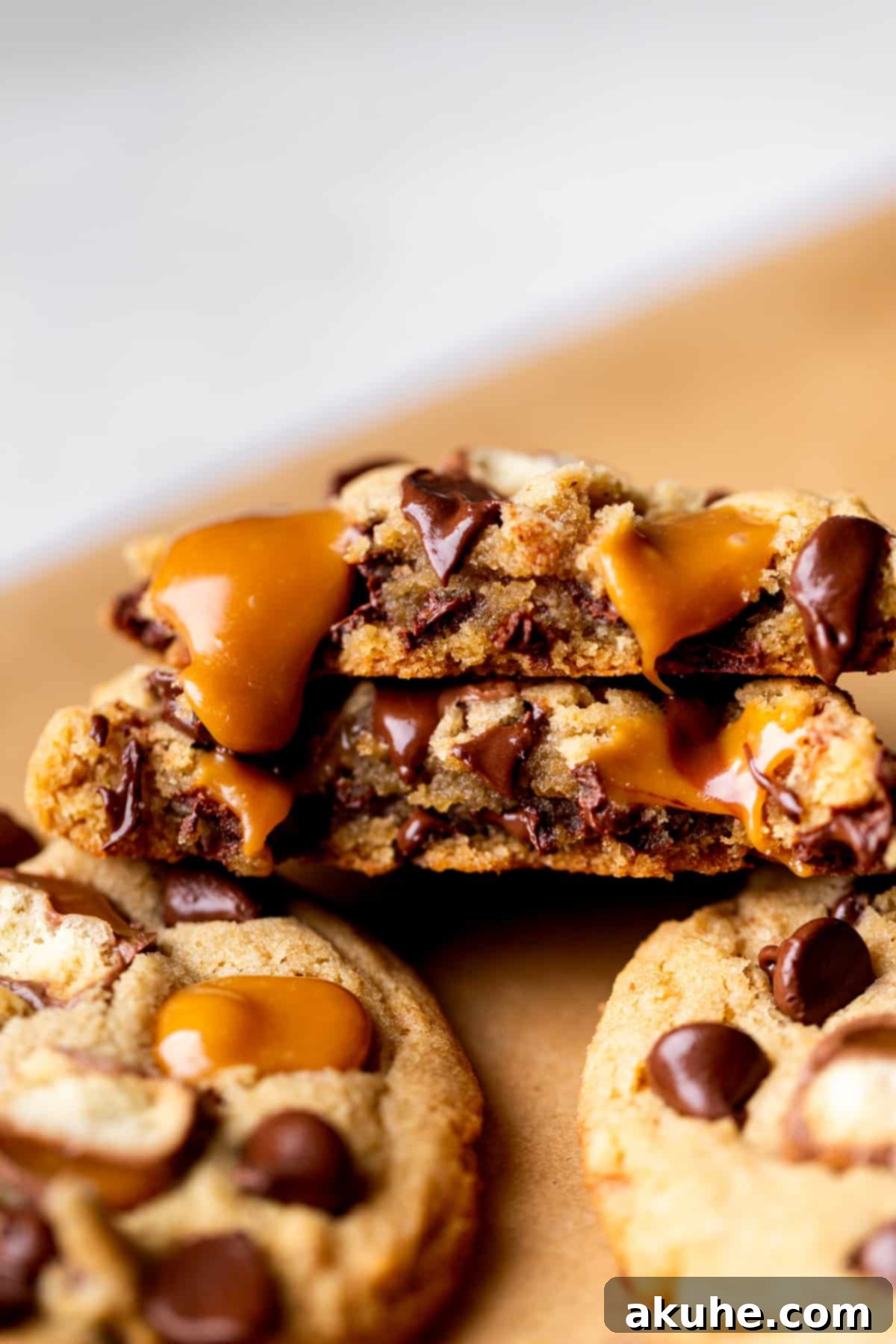 A Twix cookie split in half, revealing its soft, chewy interior with melted chocolate chips, Twix pieces, and caramel.