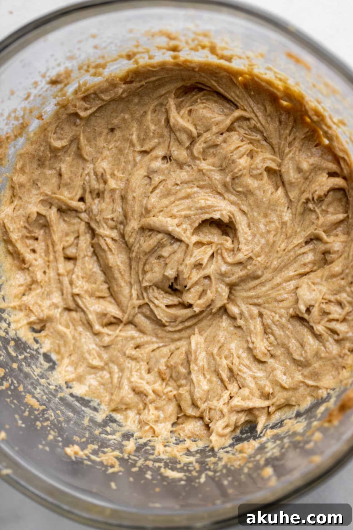 Wet ingredients (butter, sugars, eggs, vanilla) being mixed in a glass bowl.