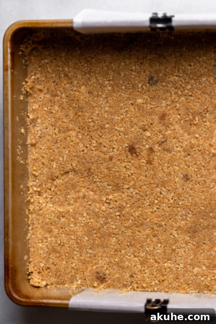 Spiced Pumpkin Caramel Cheesecake Bars 4 Graham cracker crust evenly pressed into the bottom of a baking pan, ready for the cheesecake filling.