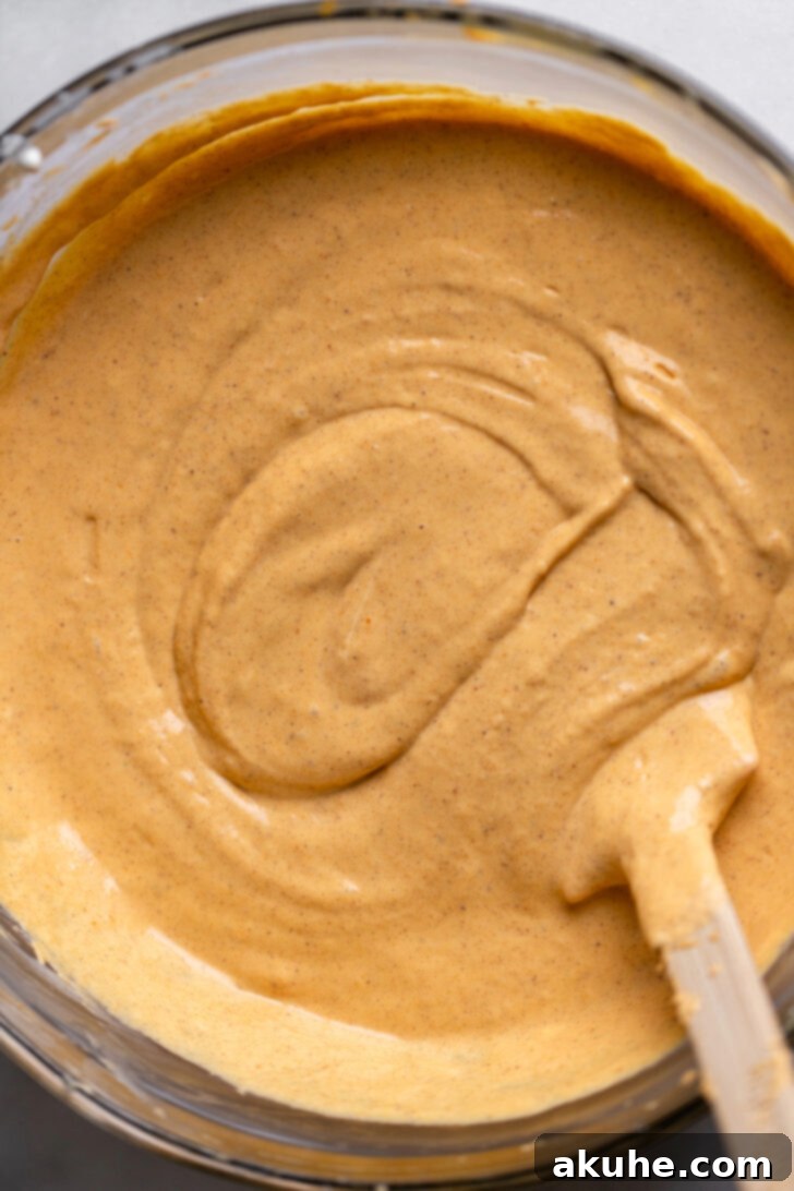 Spiced Pumpkin Caramel Cheesecake Bars 5 Creamy pumpkin cheesecake batter in a mixing bowl, ready to be poured over the crust.