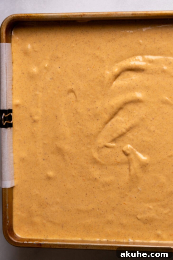 Spiced Pumpkin Caramel Cheesecake Bars 6 Pumpkin cheesecake batter spread smoothly over the pre-baked graham cracker crust in a baking pan.