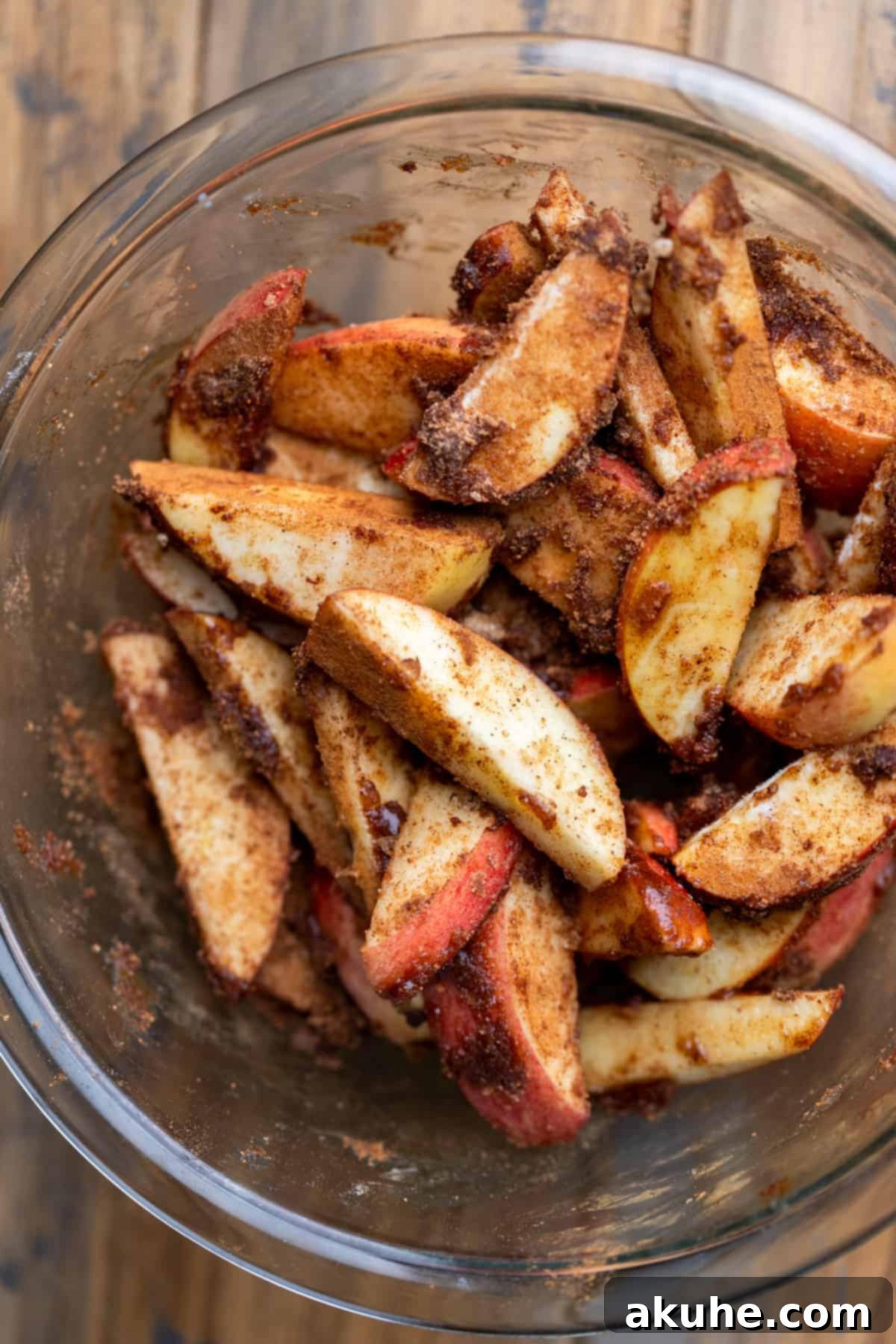Golden Apple Puff Tart 4 Close-up of caramel-coated apple slices in a clear glass bowl, glistening and ready for baking.