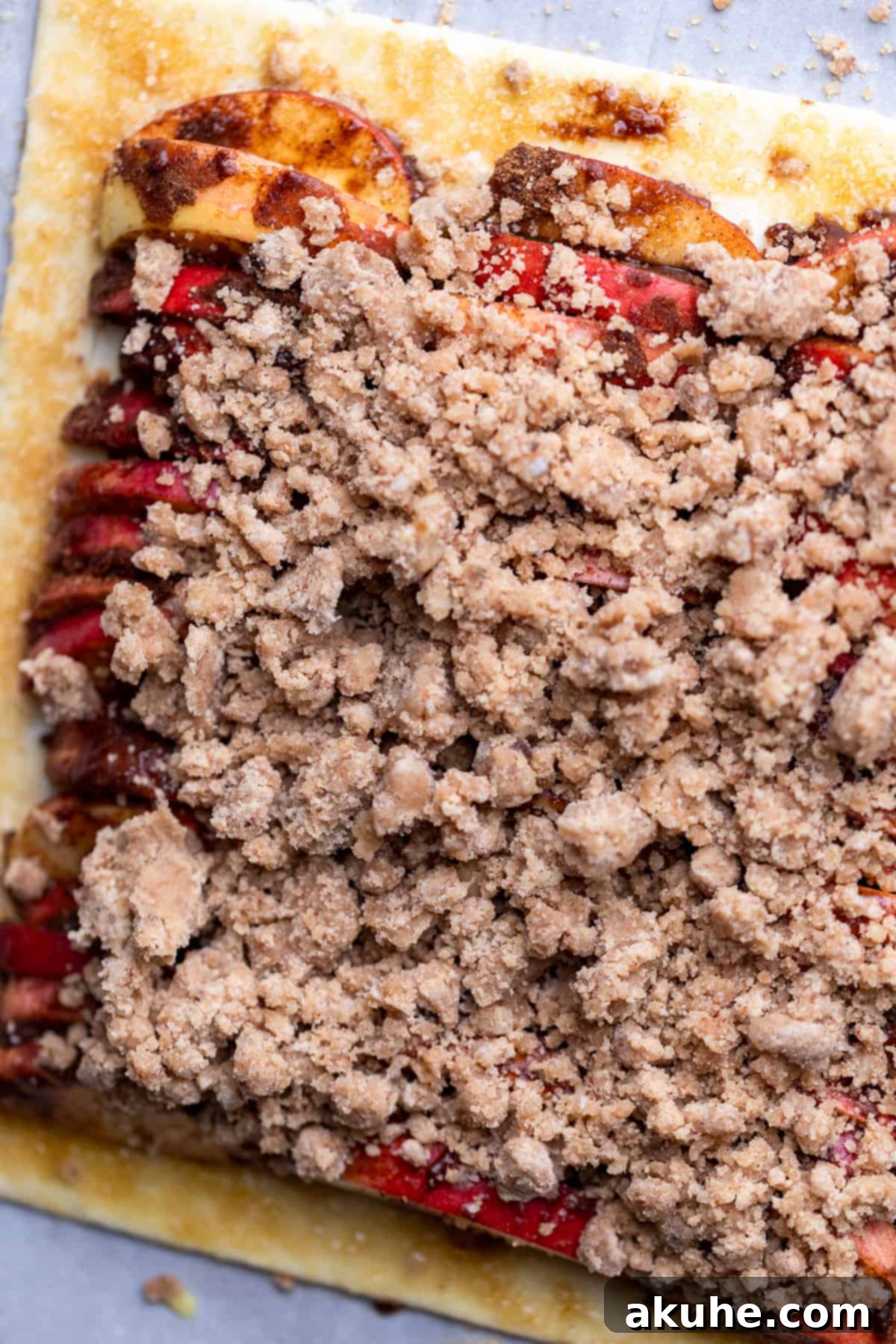 Golden Apple Puff Tart 8 Streusel topping generously sprinkled over the apple slices on the puff pastry, adding a final layer of texture and flavor.