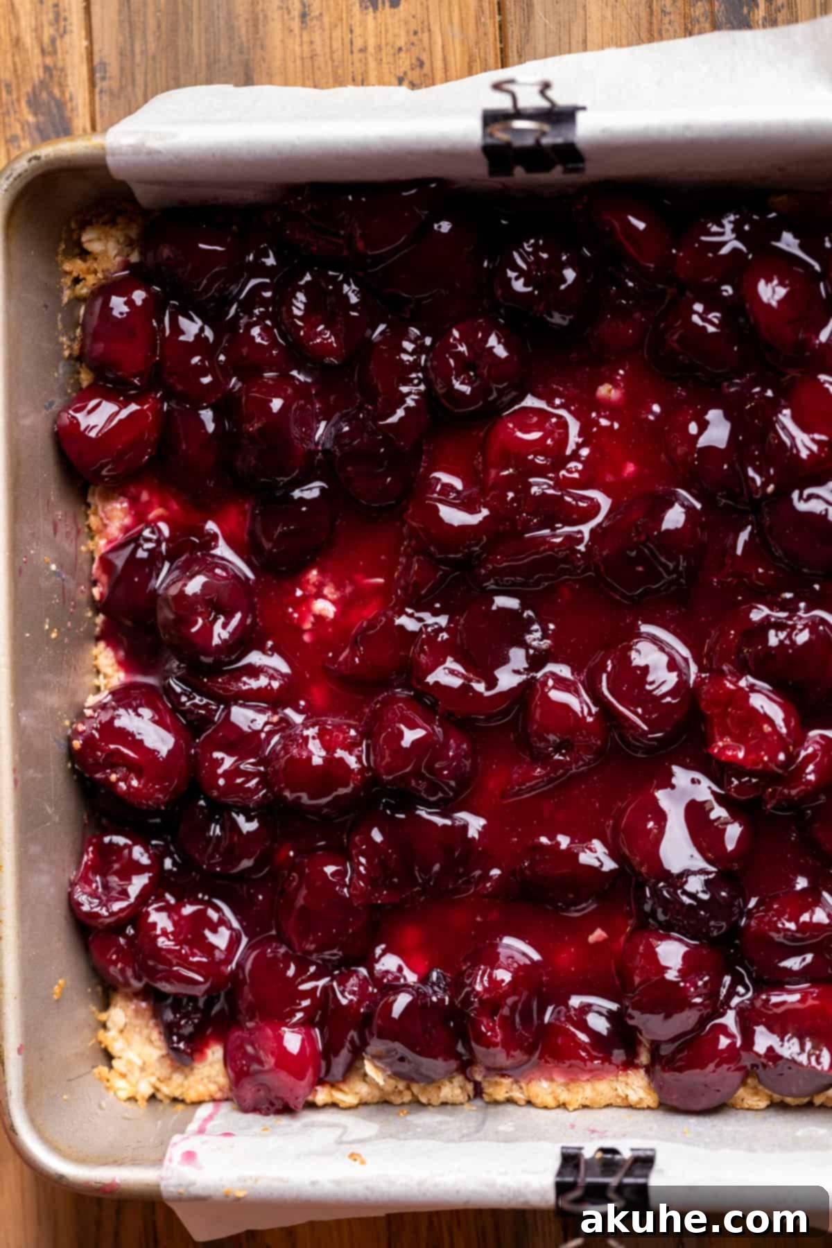 Classic Cherry Pie Bars 7 Vibrant cherry pie filling spread evenly over the pre-baked oatmeal crumble crust in a baking pan.