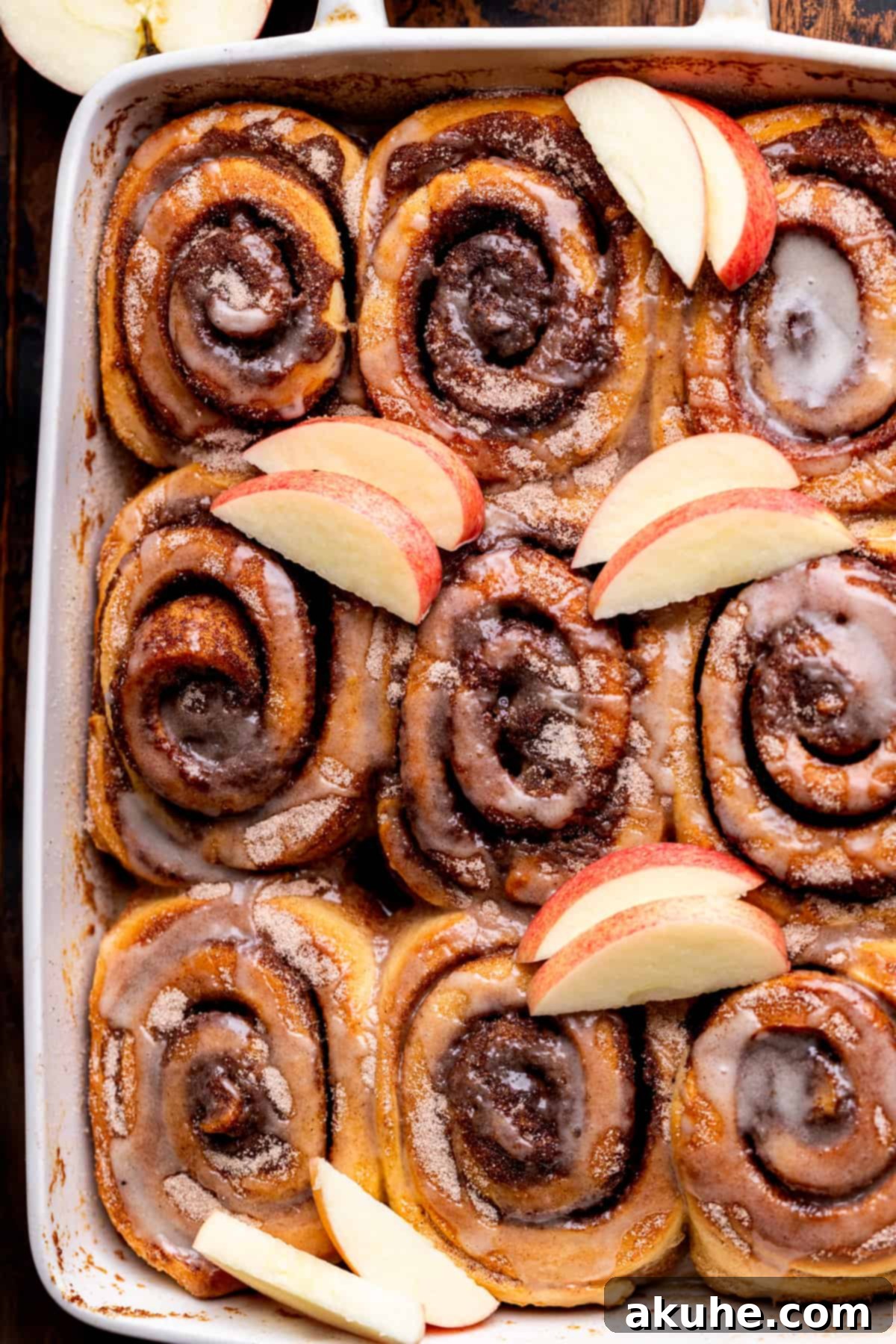 Spiced Apple Cider Cinnamon Rolls 9 An overhead shot showcasing nine perfectly baked and glazed apple cider cinnamon rolls in a pan.