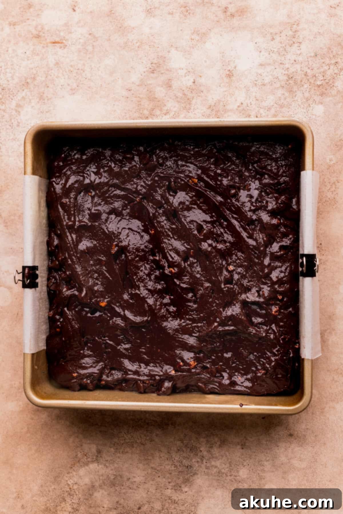 Pecan Caramel Fudge Brownies 7 Raw brownie batter spread evenly in a parchment-lined baking pan, ready for the oven.