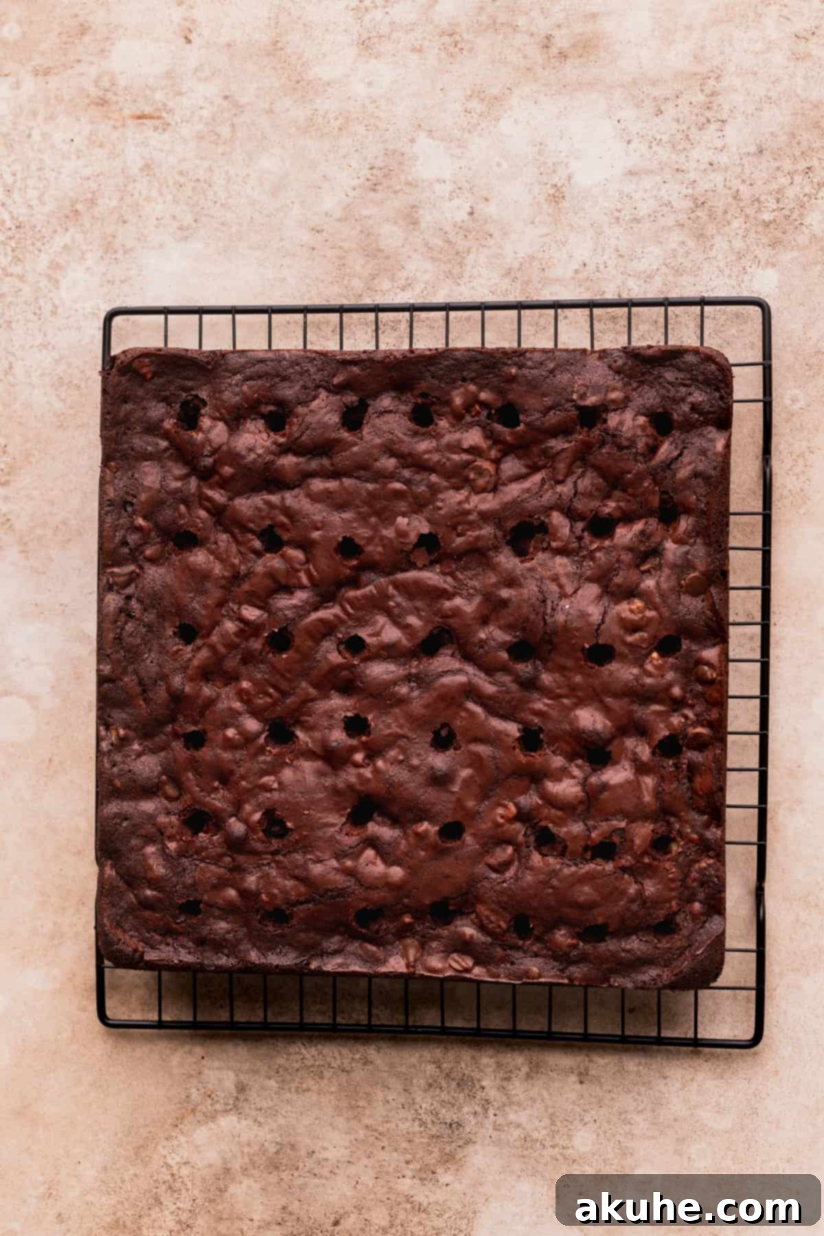 Pecan Caramel Fudge Brownies 9 A baked brownie slab with uniformly poked holes, ready for caramel filling.