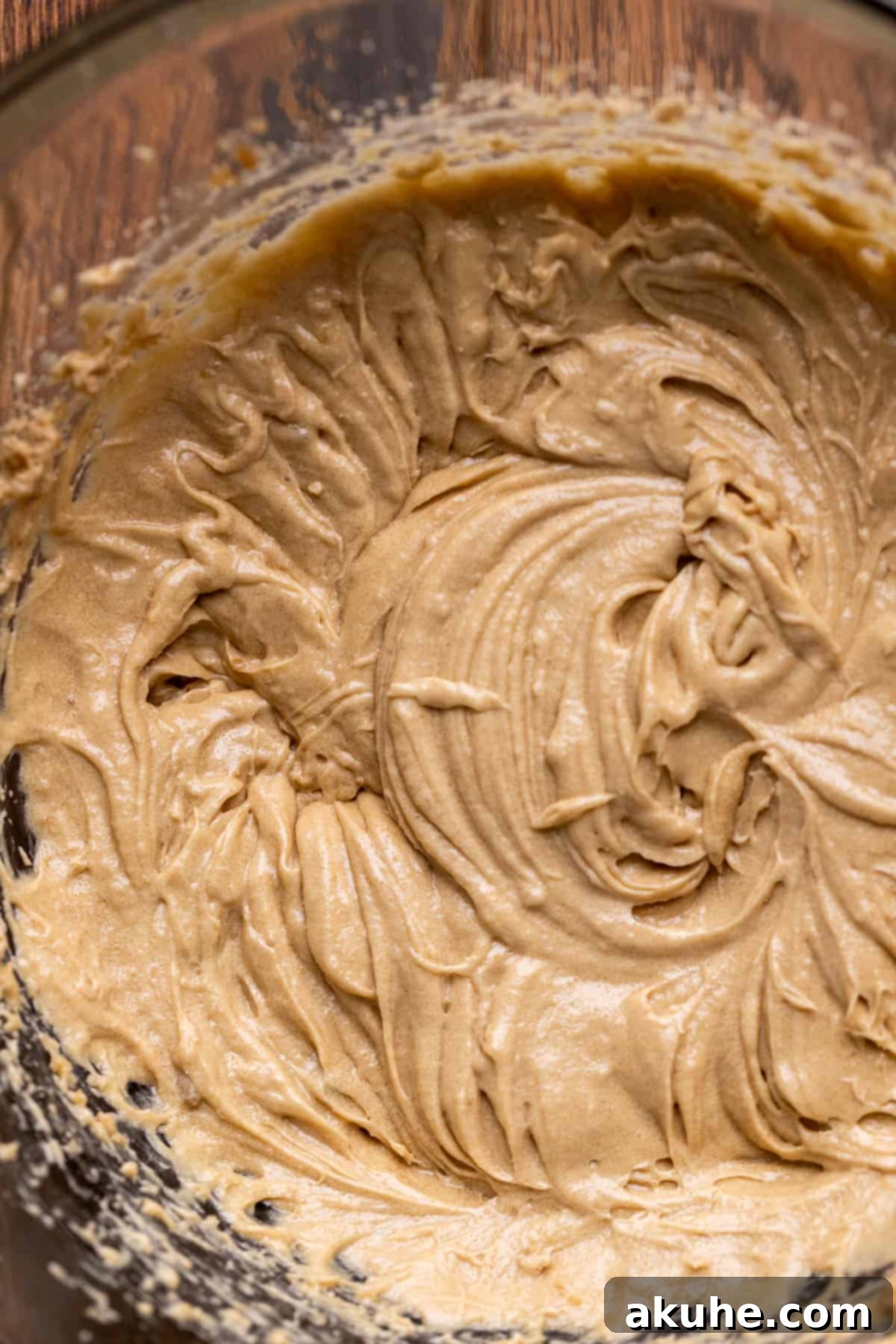 Close-up of wet ingredients (melted butter, sugars, eggs, vanilla) being mixed in a bowl.