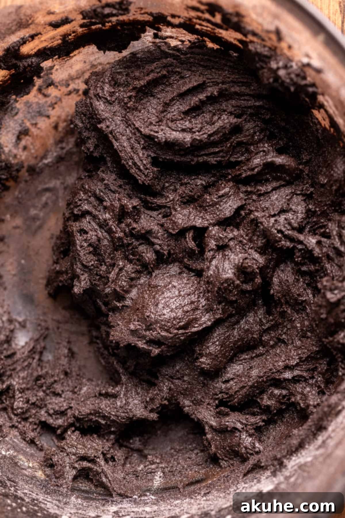 Rich black cocoa cookie dough in a clear glass bowl, showcasing its dark color and smooth texture.