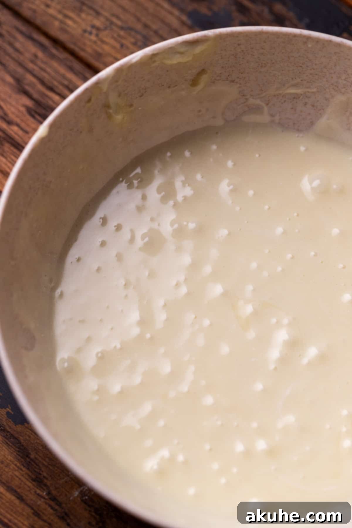 Smooth and glossy white chocolate ganache in a small bowl.