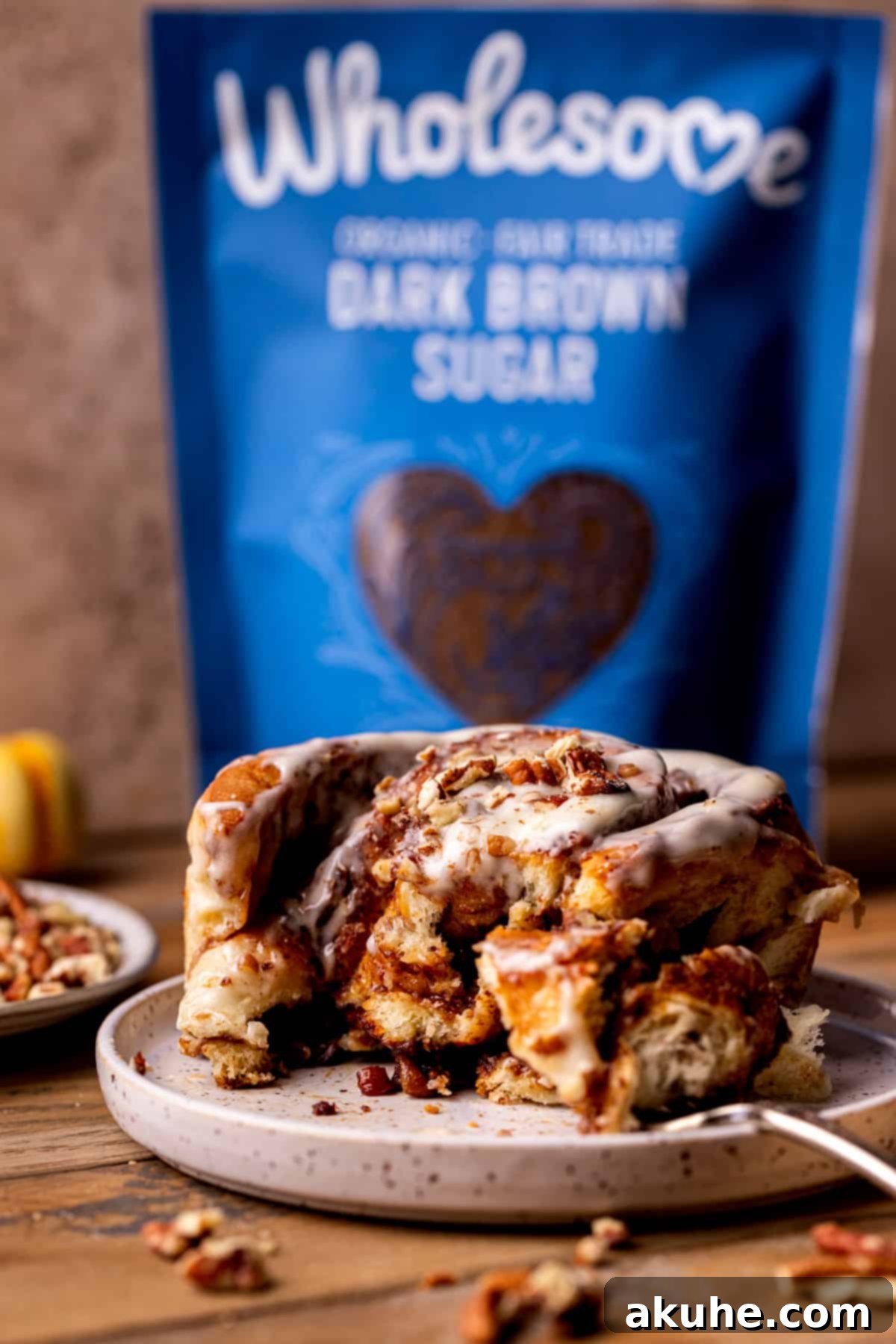 A single pecan pie cinnamon roll served on a white plate, showcasing its golden crust and creamy glaze.