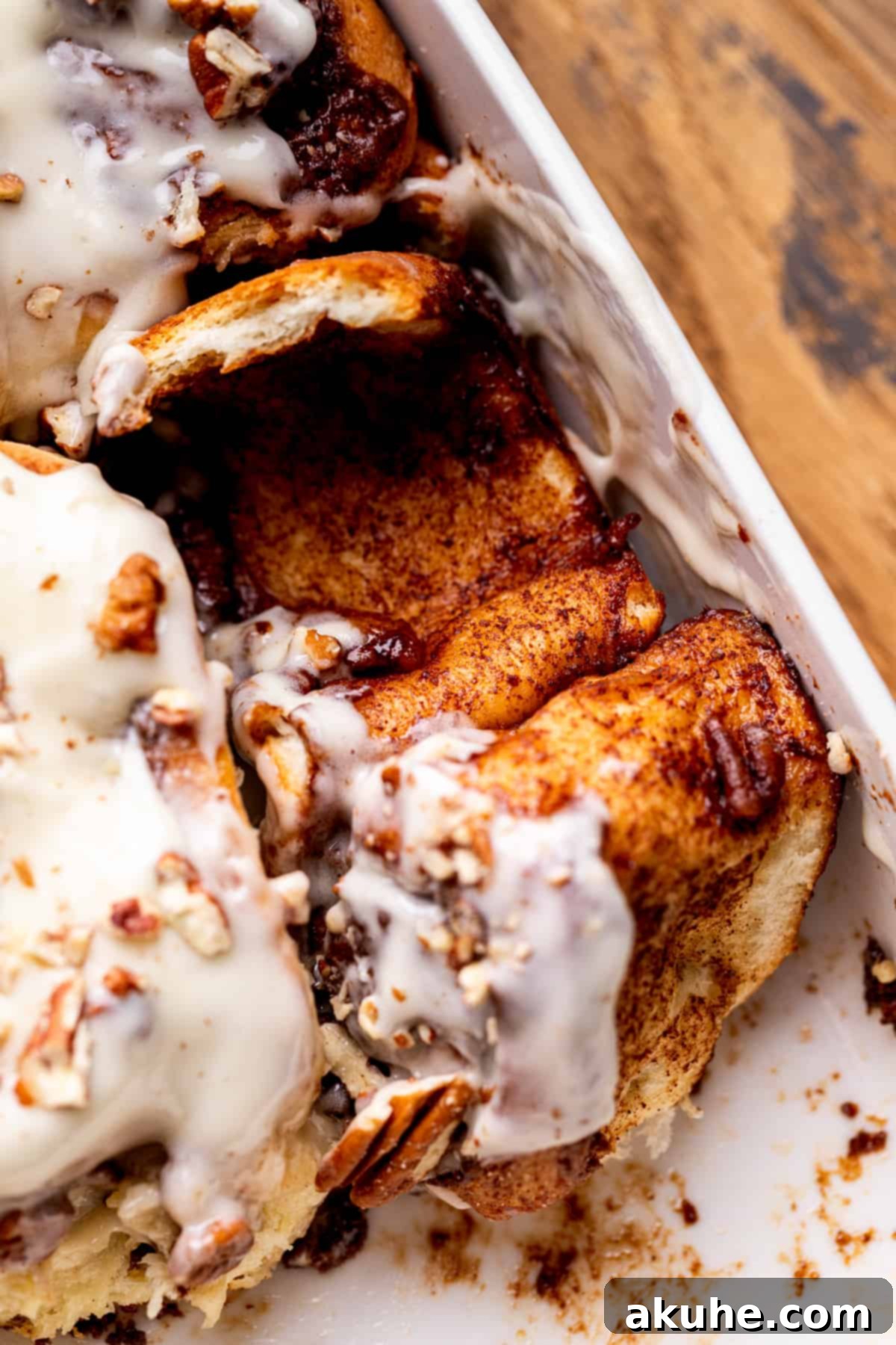Close-up of a pecan pie cinnamon roll split open, revealing its gooey layers of filling.