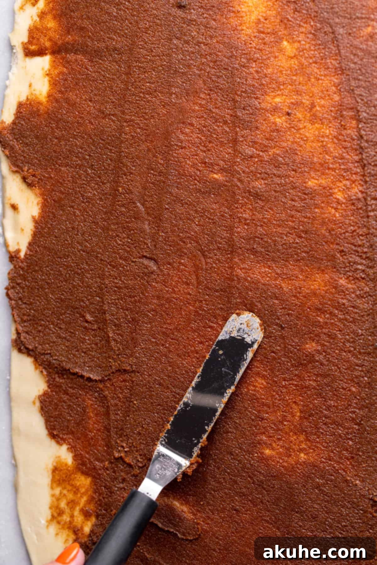 Spreading the rich cinnamon filling smoothly over the dough.