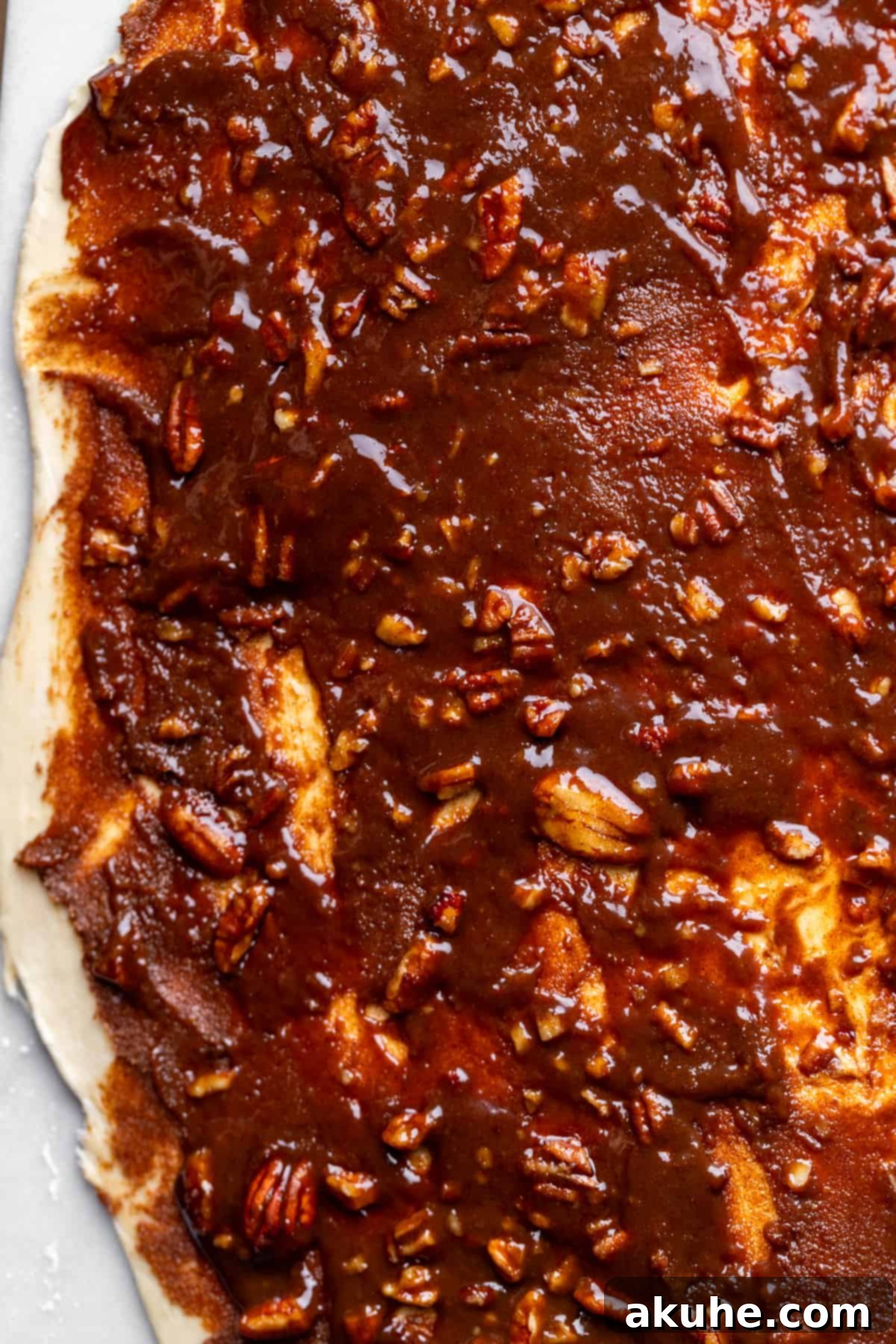 Layers of gooey pecan pie filling spread over the cinnamon-coated dough.