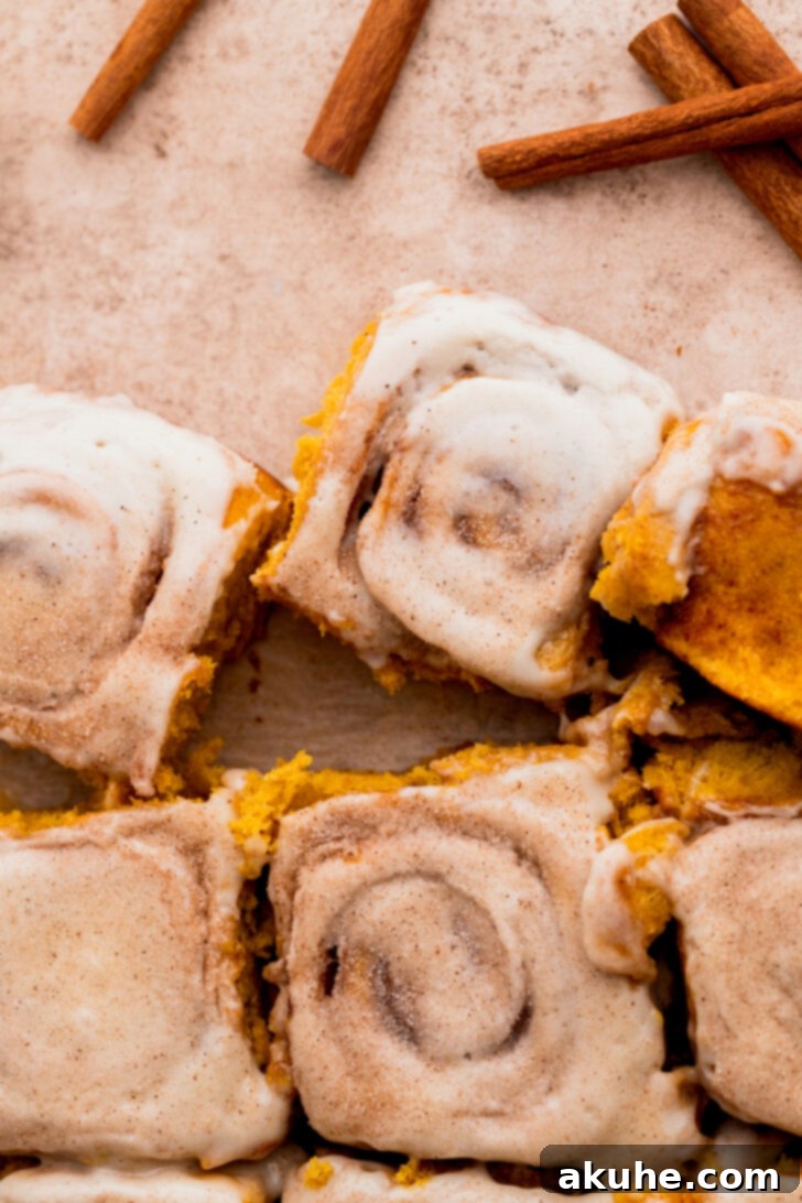 Top view of the center of freshly baked pumpkin cinnamon rolls, showcasing their gooey filling and rich cream cheese icing.