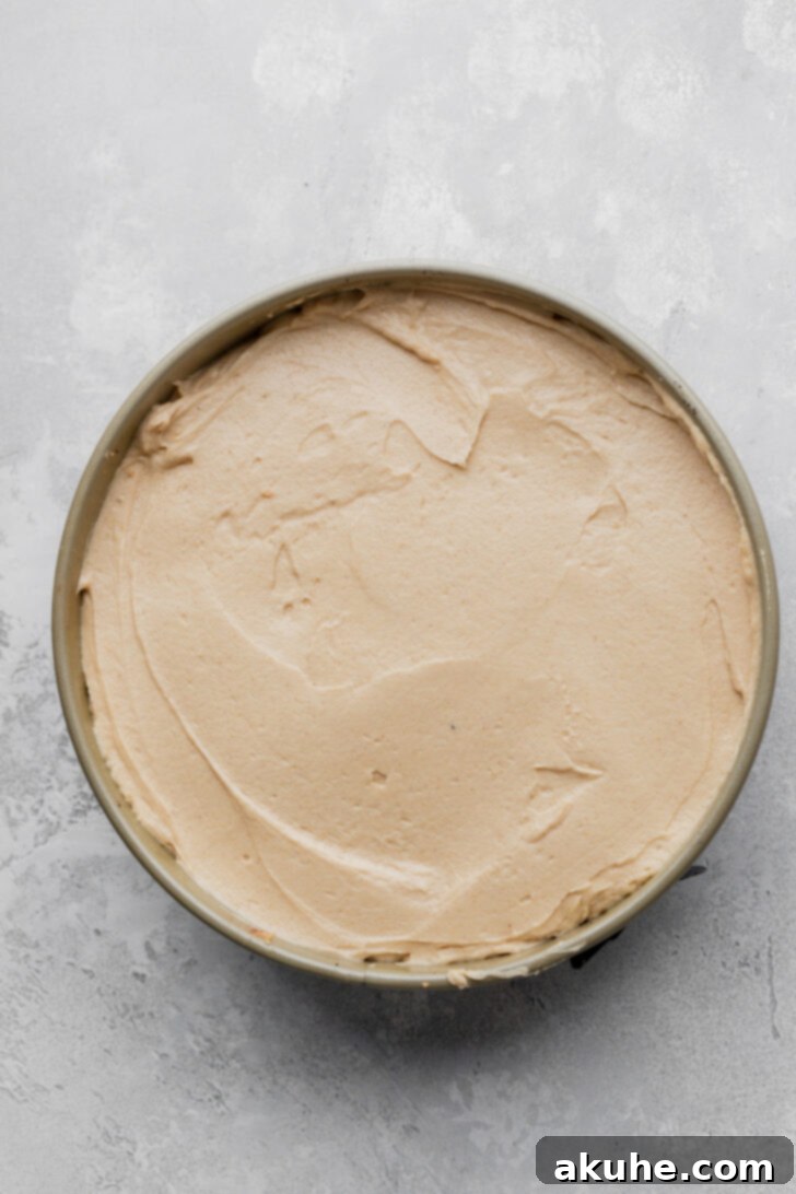 The remaining peanut butter batter smoothed over the peanut butter cups in the pie pan, creating an even surface.