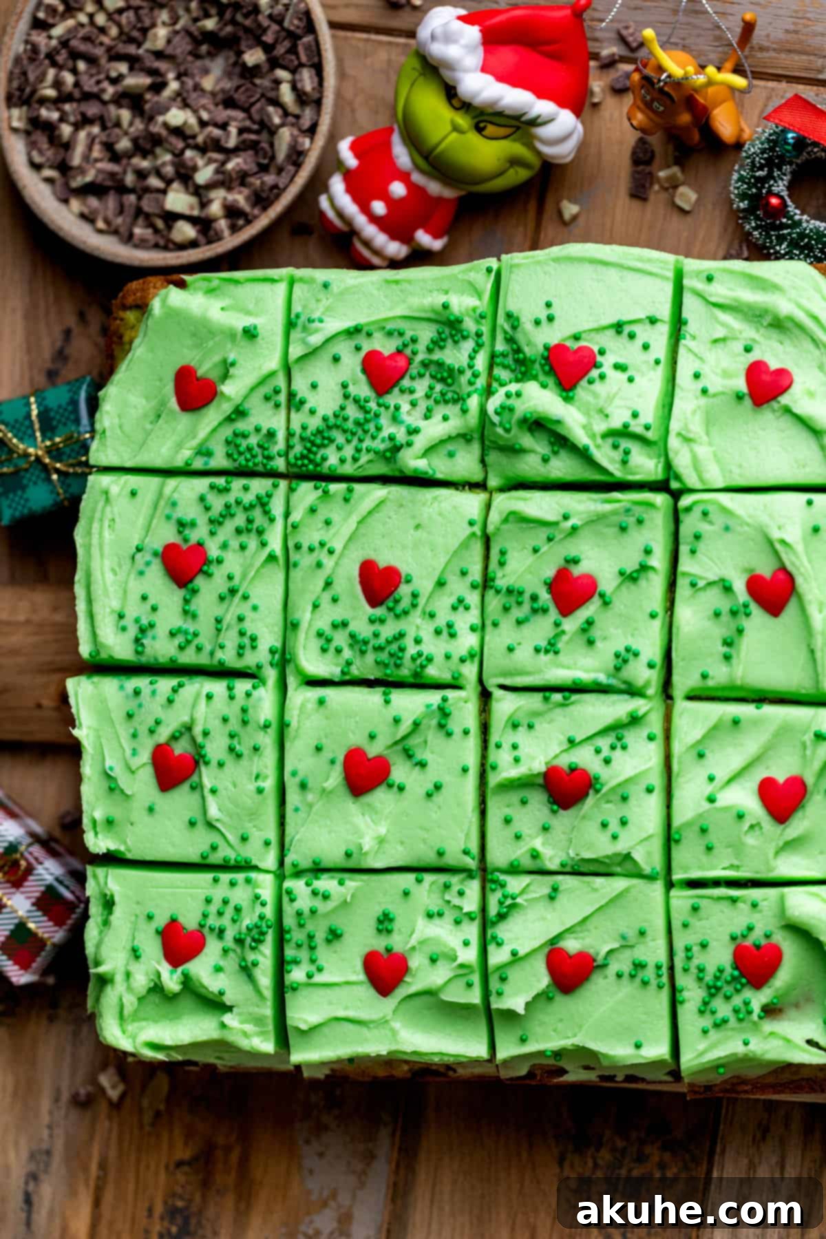 Grinchy Holiday Cake 2 Top view of a festive green Grinch cake, decorated with a single red heart sprinkle and luscious cream cheese frosting, ready for a Christmas celebration.