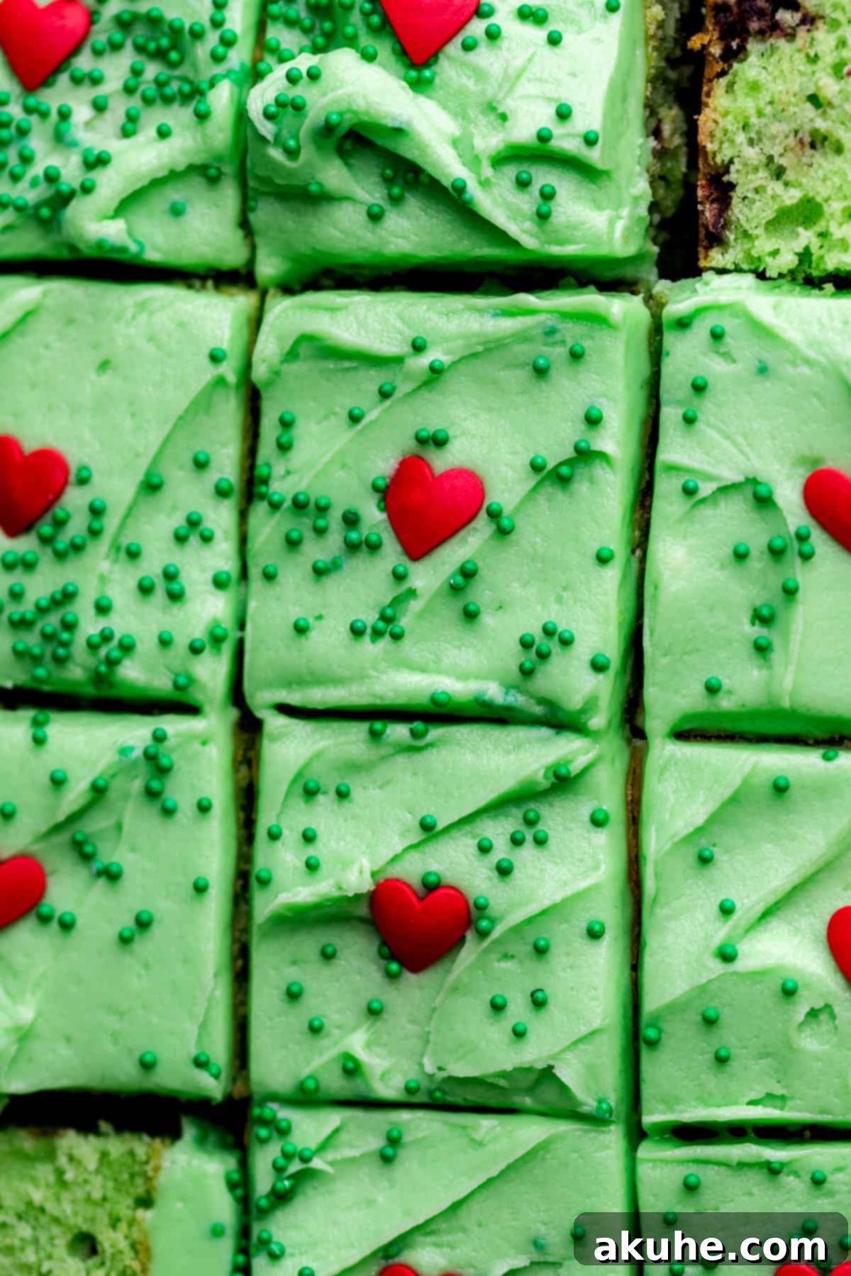 Grinchy Holiday Cake 3 Close-up view of the top of a Grinch cake, showcasing the smooth green cream cheese frosting and a perfectly placed red heart sprinkle.