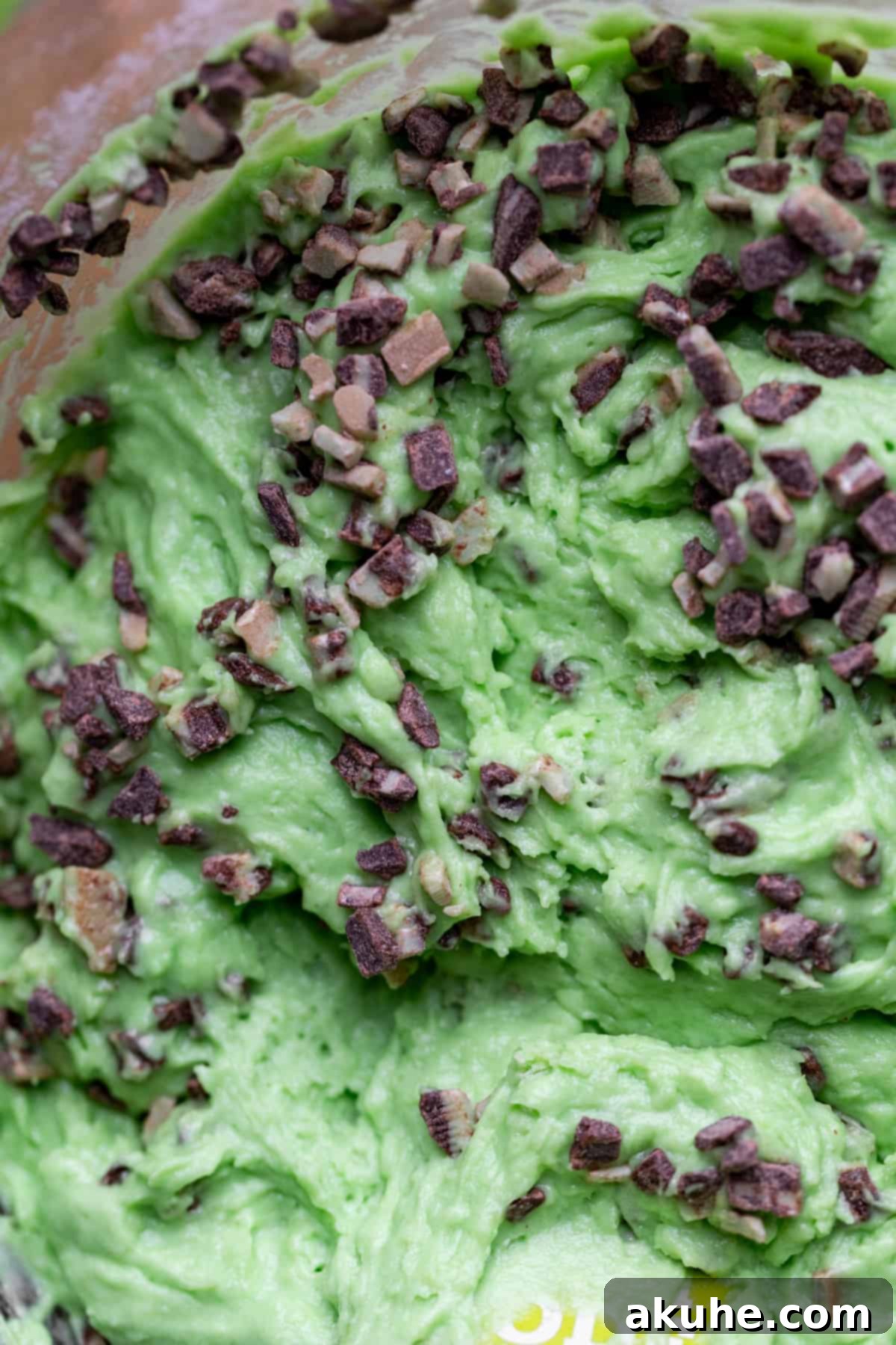 Grinchy Holiday Cake 4 Vibrant green vanilla mint cake batter resting in a clear glass bowl, showcasing its smooth texture and color.