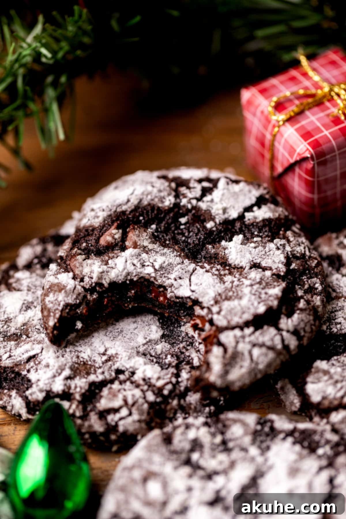 A perfectly baked, fudgy chocolate crinkle cookie with a bite missing, showcasing its soft interior.