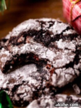 Bite missing from a chocolate crinkle cookie, revealing a moist, fudgy interior.