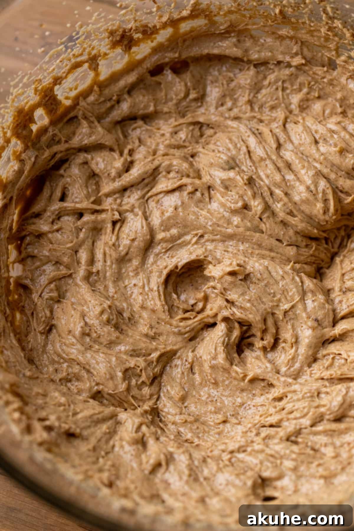Wet ingredients beaten in a glass bowl, showcasing a pale, fluffy texture.