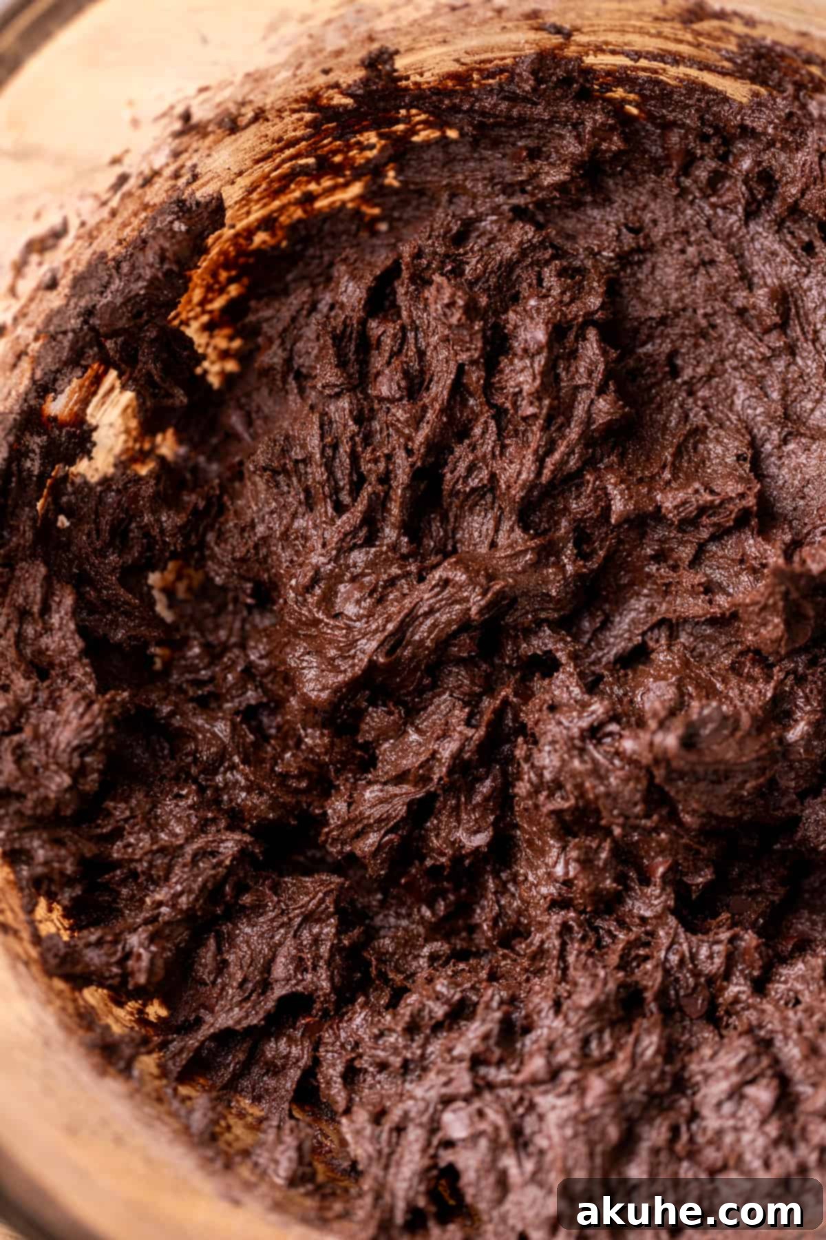 Rich chocolate cookie dough after all ingredients are combined, resting in a glass bowl.