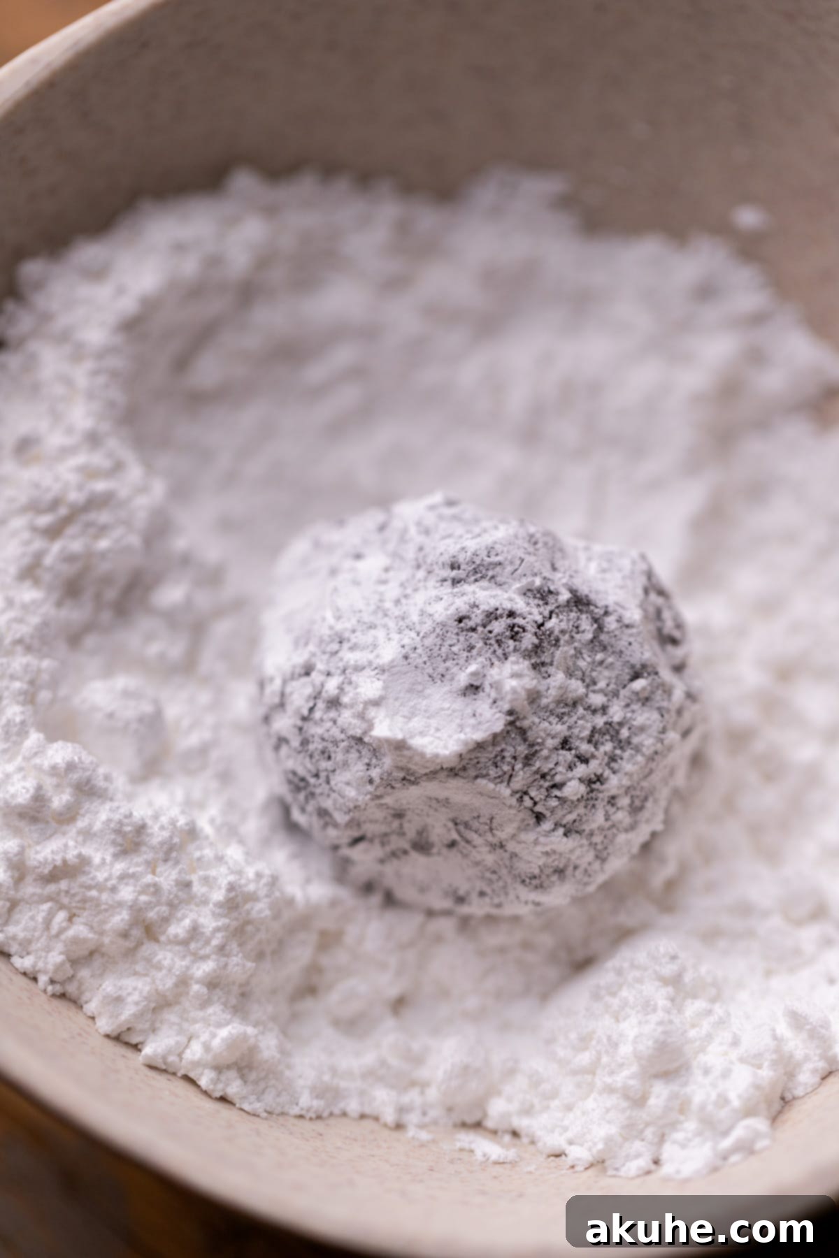 A ball of chocolate cookie dough, now generously coated in powdered sugar.