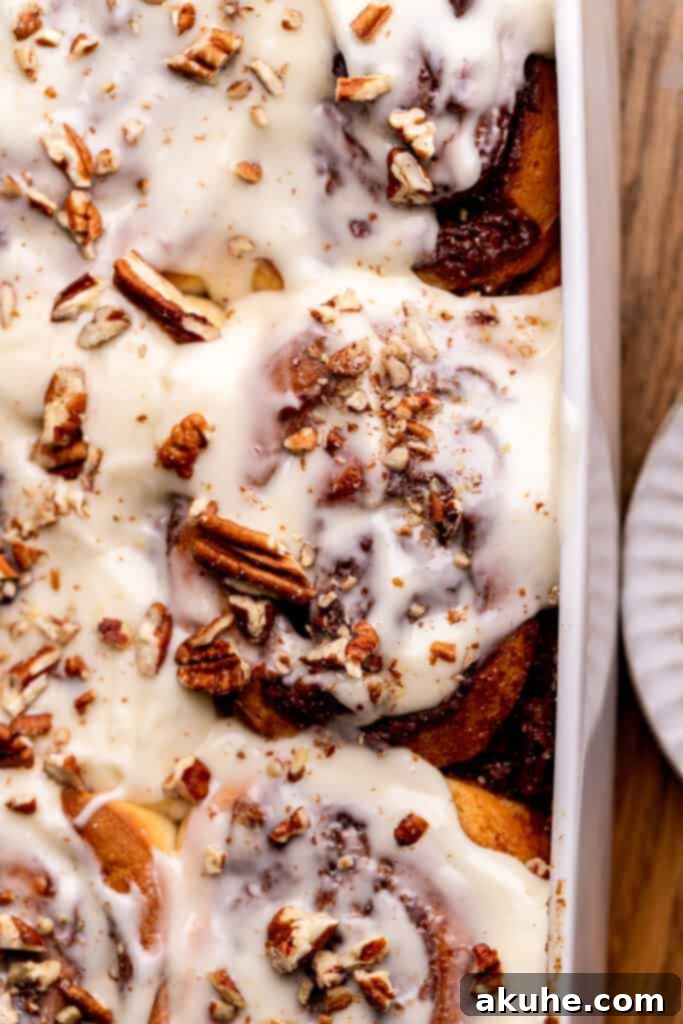 An inviting overhead shot of decadent pecan pie cinnamon rolls, featuring a rich, sticky pecan topping with a golden sheen.