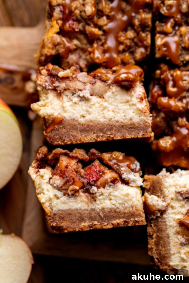 Spiced Caramel Apple Cheesecake Bars 3 Two caramel apple cheesecake bars displayed on their side, highlighting the layered structure.