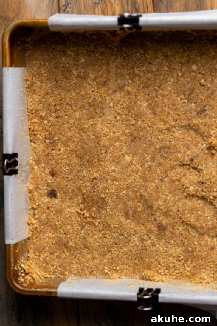 Spiced Caramel Apple Cheesecake Bars 4 Graham cracker crust pressed firmly into the bottom of a square baking pan.