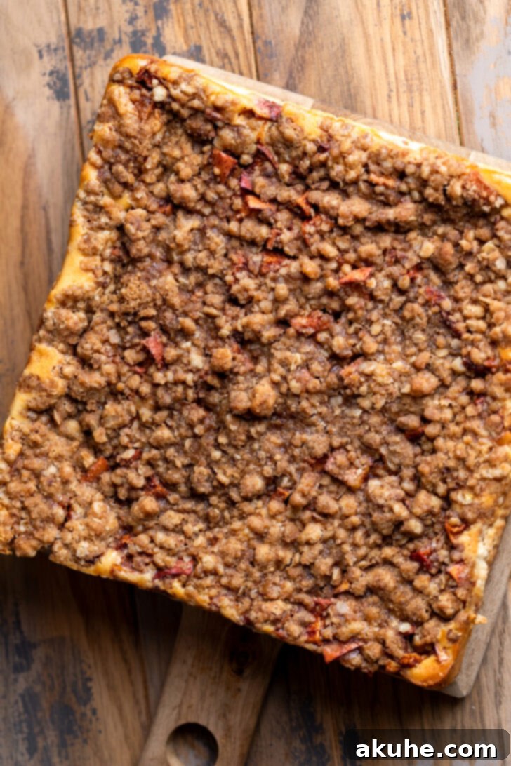 Spiced Caramel Apple Cheesecake Bars 10 Freshly baked caramel apple cheesecake bars cooling on a wooden board.