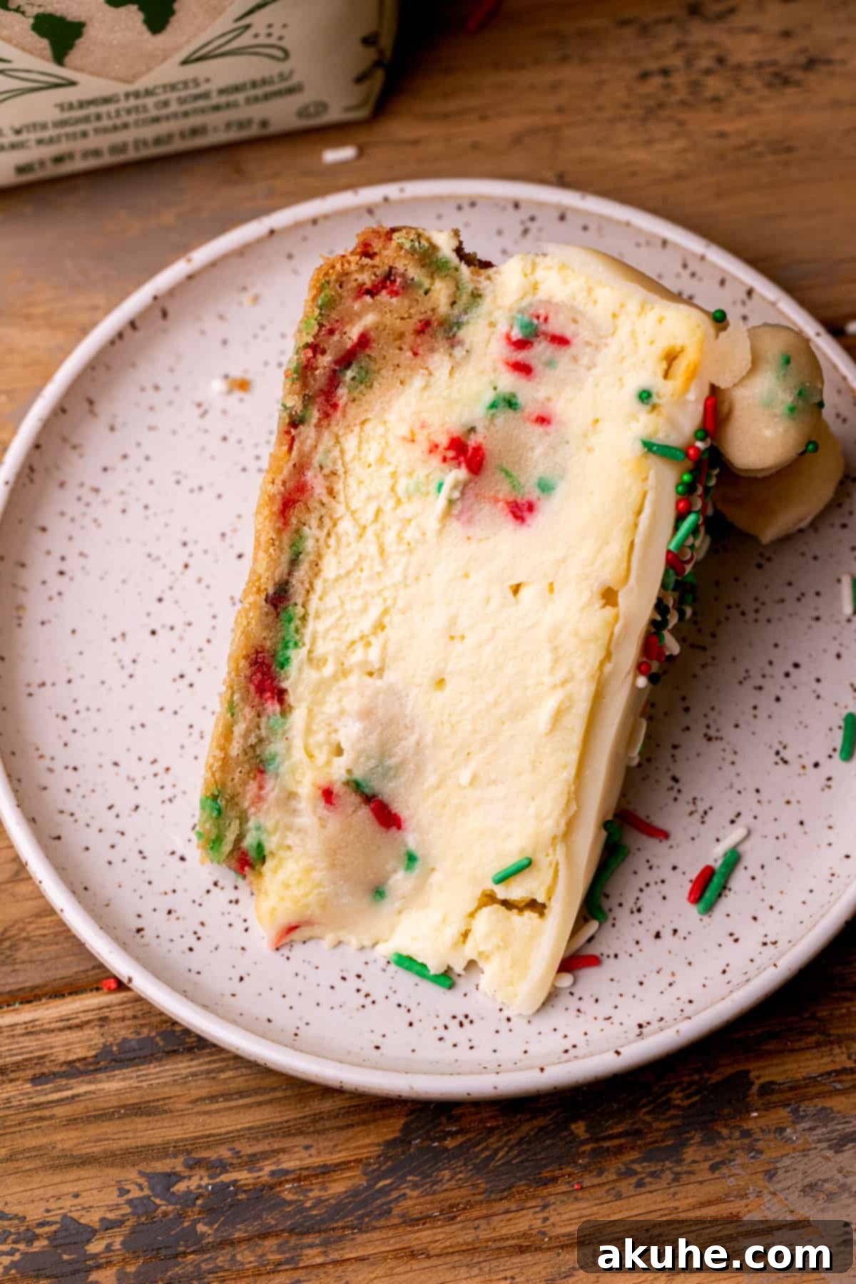 Sugar Cookie Dream Cheesecake 11 A single, perfectly cut slice of sugar cookie cheesecake presented on a white plate, highlighting its layers.