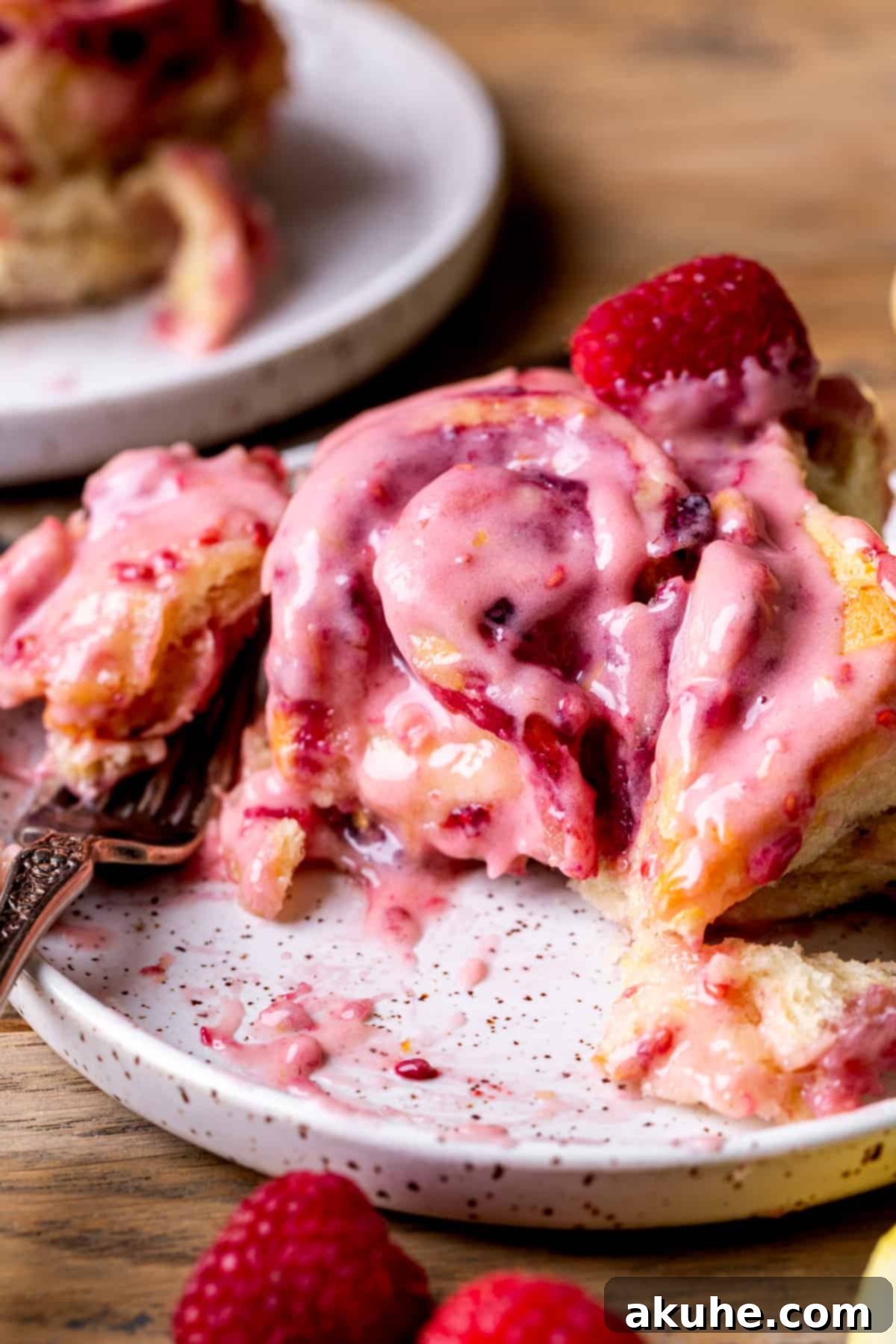 Tangy Lemon Raspberry Buns 8 A close-up shot of a lemon raspberry roll with a bite taken out, revealing the soft interior and delicious filling.
