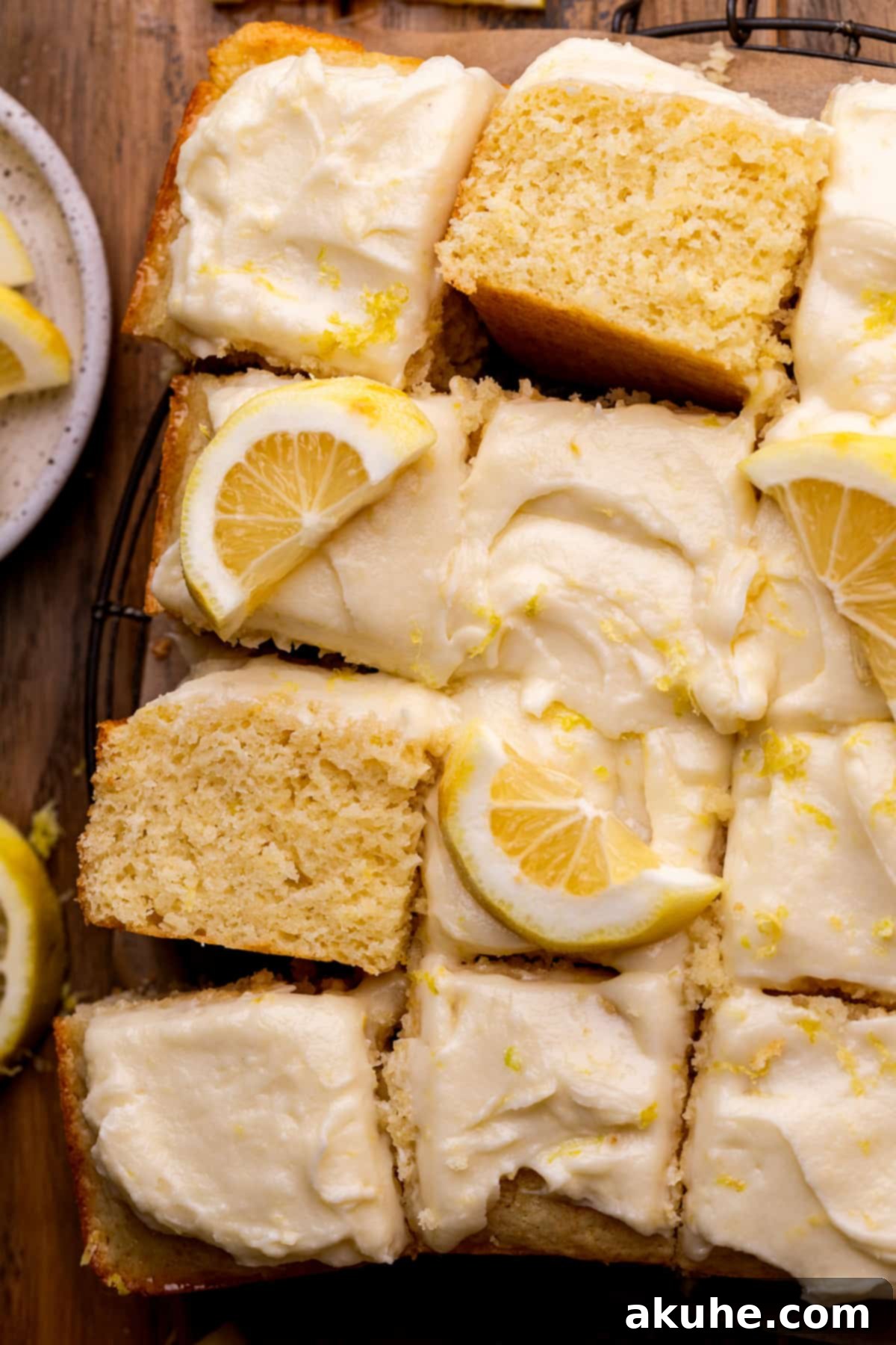 A perfectly golden lemon drizzle cake on a pristine white platter, showcasing its delightful frosting and inviting texture.
