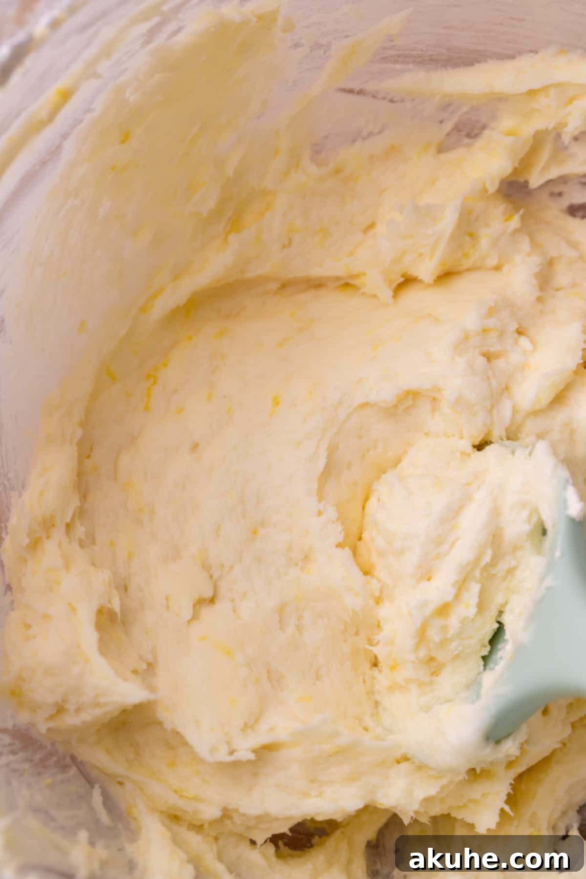 Lush lemon cream cheese frosting in a glass bowl, showcasing its smooth and inviting texture.