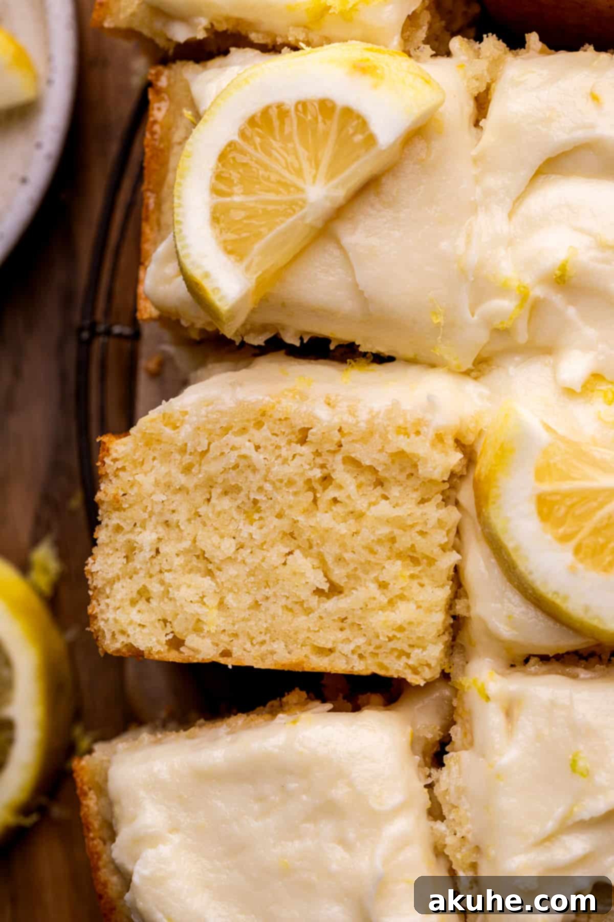 A single slice of lemon drizzle cake, exquisitely presented on its side, ready to be enjoyed.